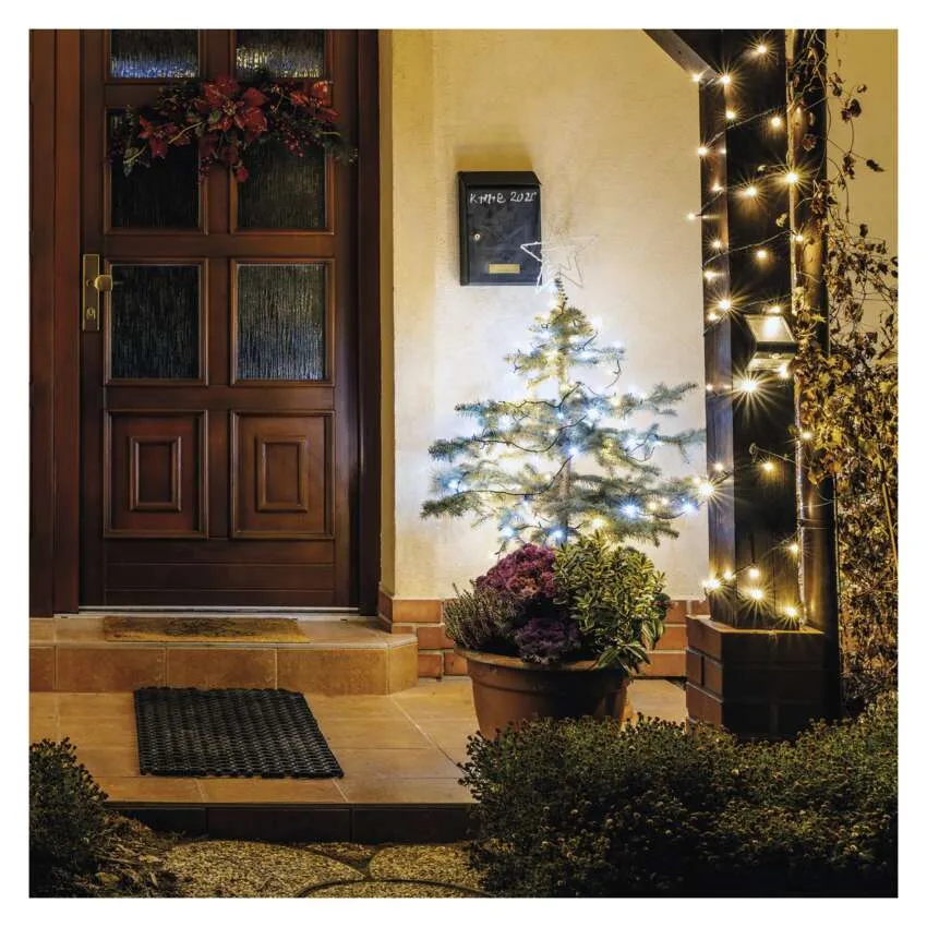 Egy díszített bejárat. Egy karácsonyfa és a fények egy ajtó mellett vannak, koszorúval. Egy postaláda látható.