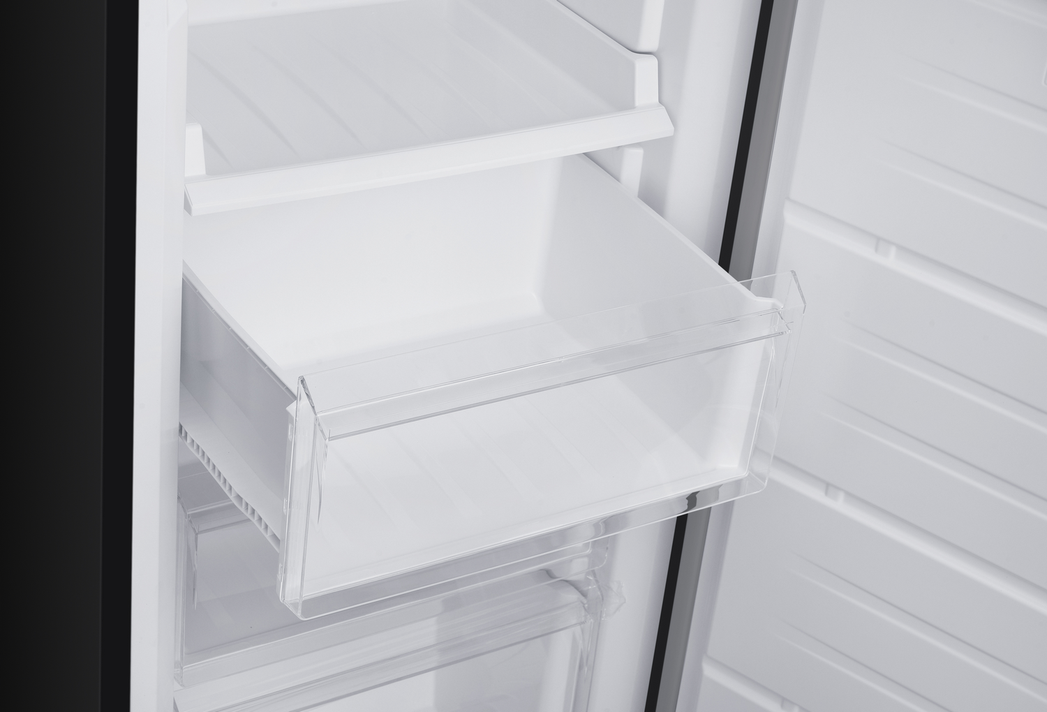 Dentro de un refrigerador, se ven cajones y estantes. Los cajones son de plástico transparente y el interior es blanco.