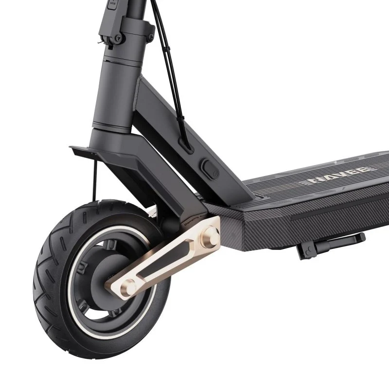 Primer plano de un patinete eléctrico negro y dorado. Son visibles la rueda delantera y la plataforma. El neumático tiene dibujo.