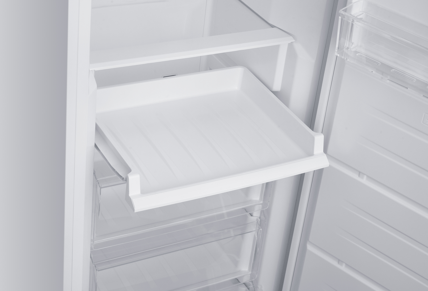 Dentro de un refrigerador blanco, una bandeja extraíble está extendida. Debajo hay cajones de plástico transparente. La puerta del refrigerador está abierta.