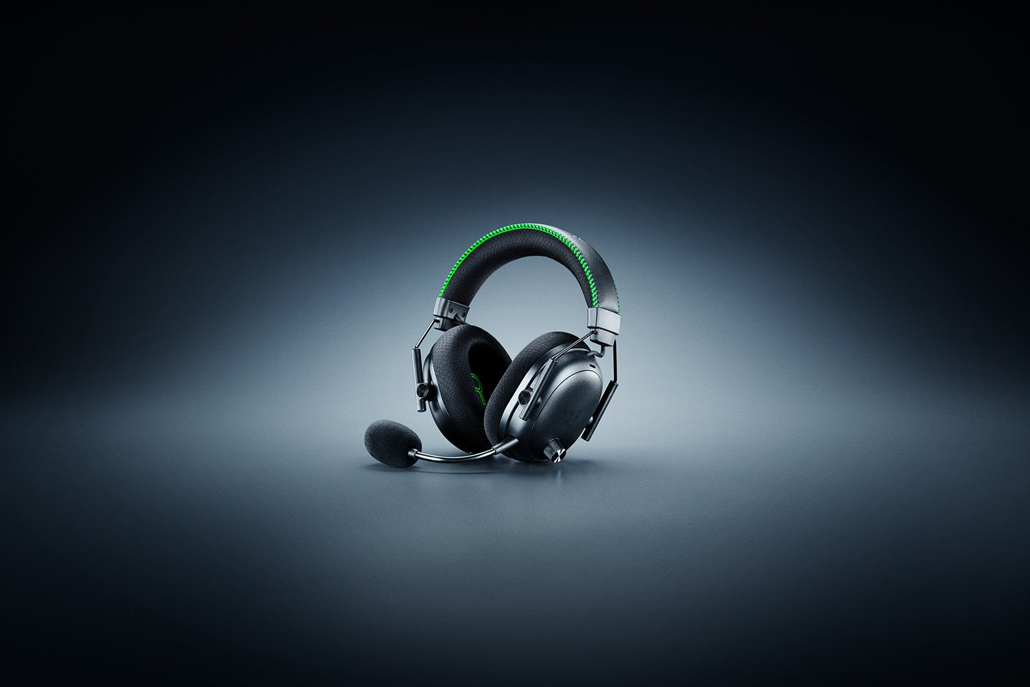 Schwarzes Gaming-Headset mit grün genähtem Stirnband und Mikrofon auf dunklem Hintergrund. Das Razer-Logo ist sichtbar.