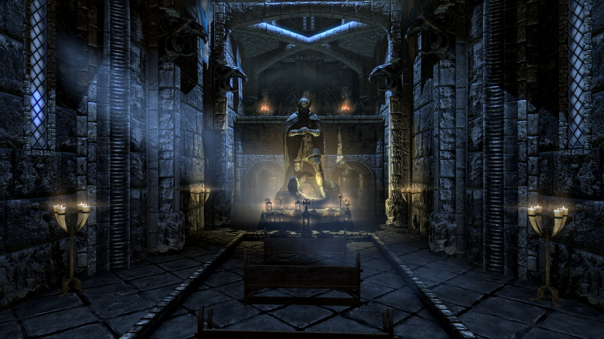 All'interno di una sala in pietra, una statua si erge. Candele e lanterne illuminano la scena. La stanza ha un'atmosfera gotica oscura.
