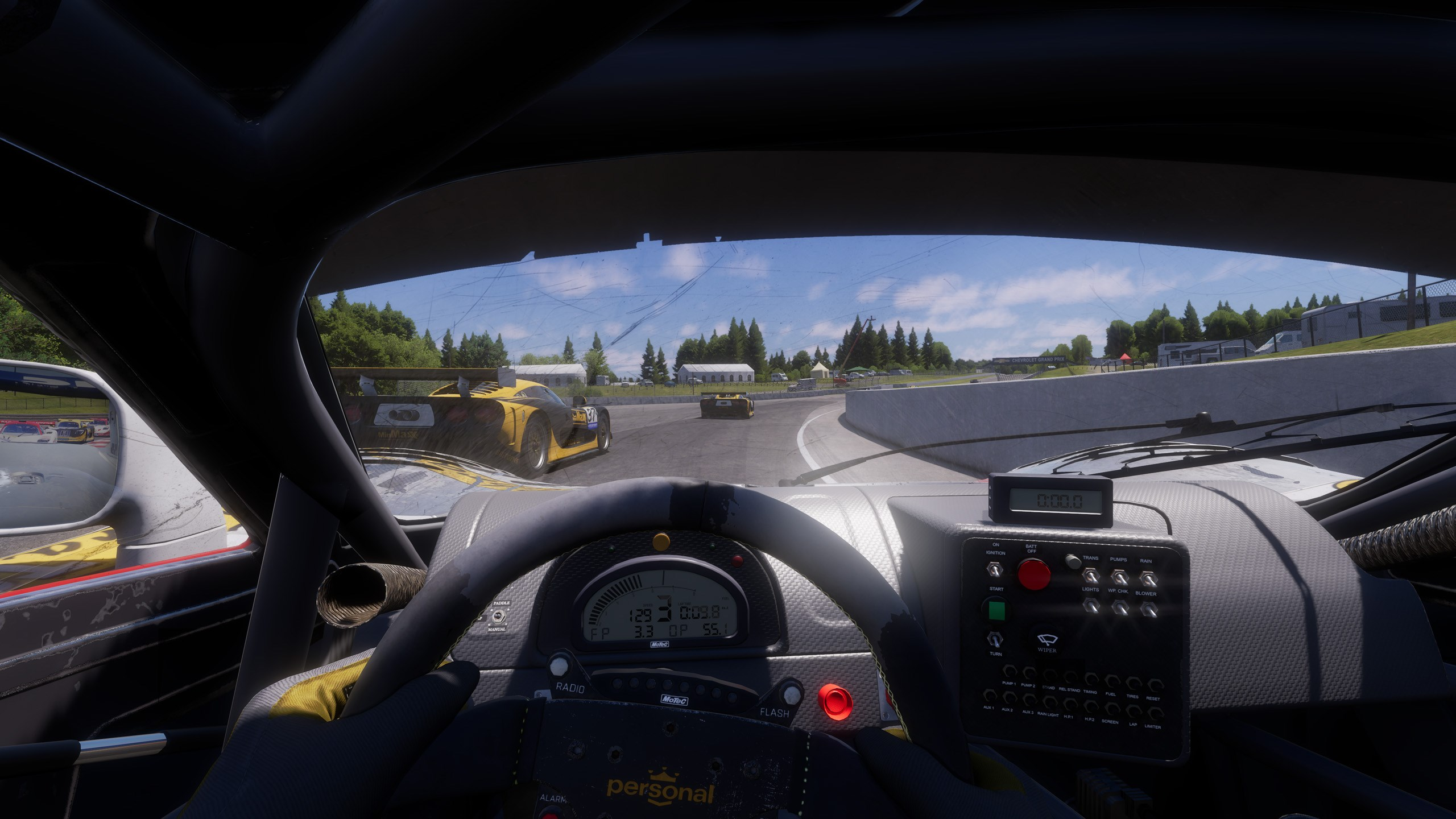 Vue de l'intérieur d'une voiture de course. Voitures de course jaunes devant. Le tableau de bord et le volant sont mis au point. La piste est visible.