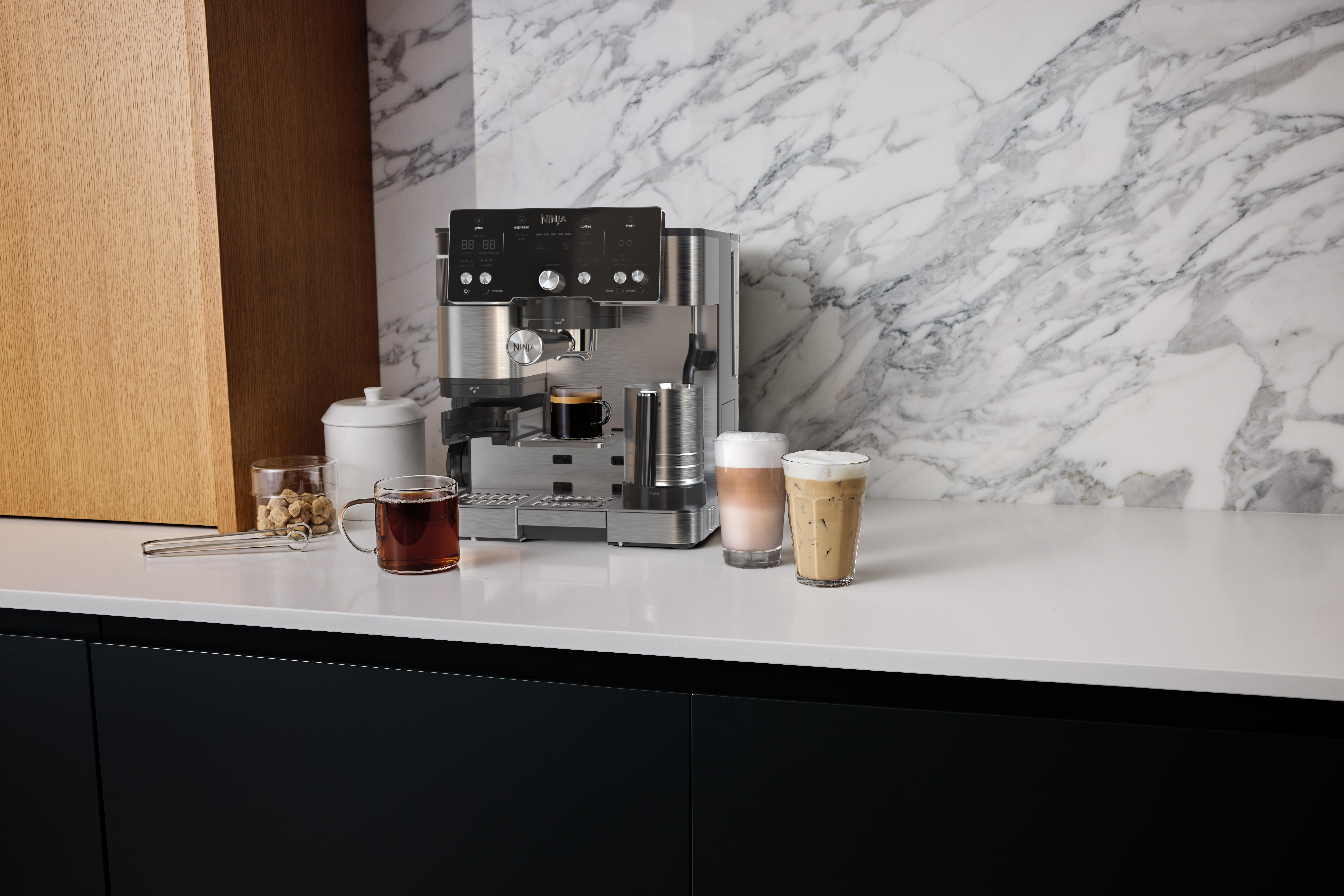 Kaffeemaschine mit Kaffee, Getränken und Zuckerwürfeln auf einer weißen Theke mit Marmorhintergrund.