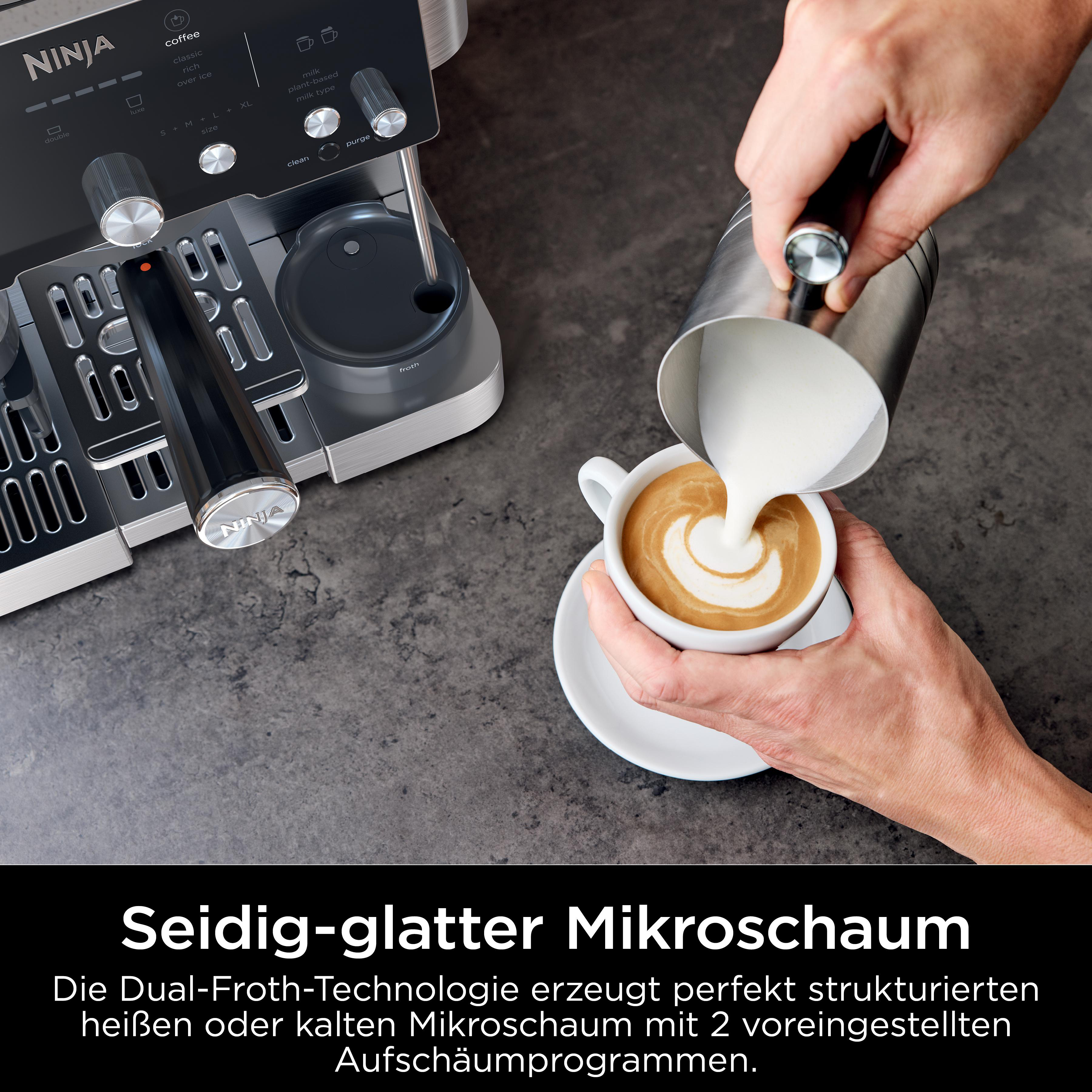 Eine Person gießt Milch in einen Latte. Eine Kaffeemaschine ist im Hintergrund.