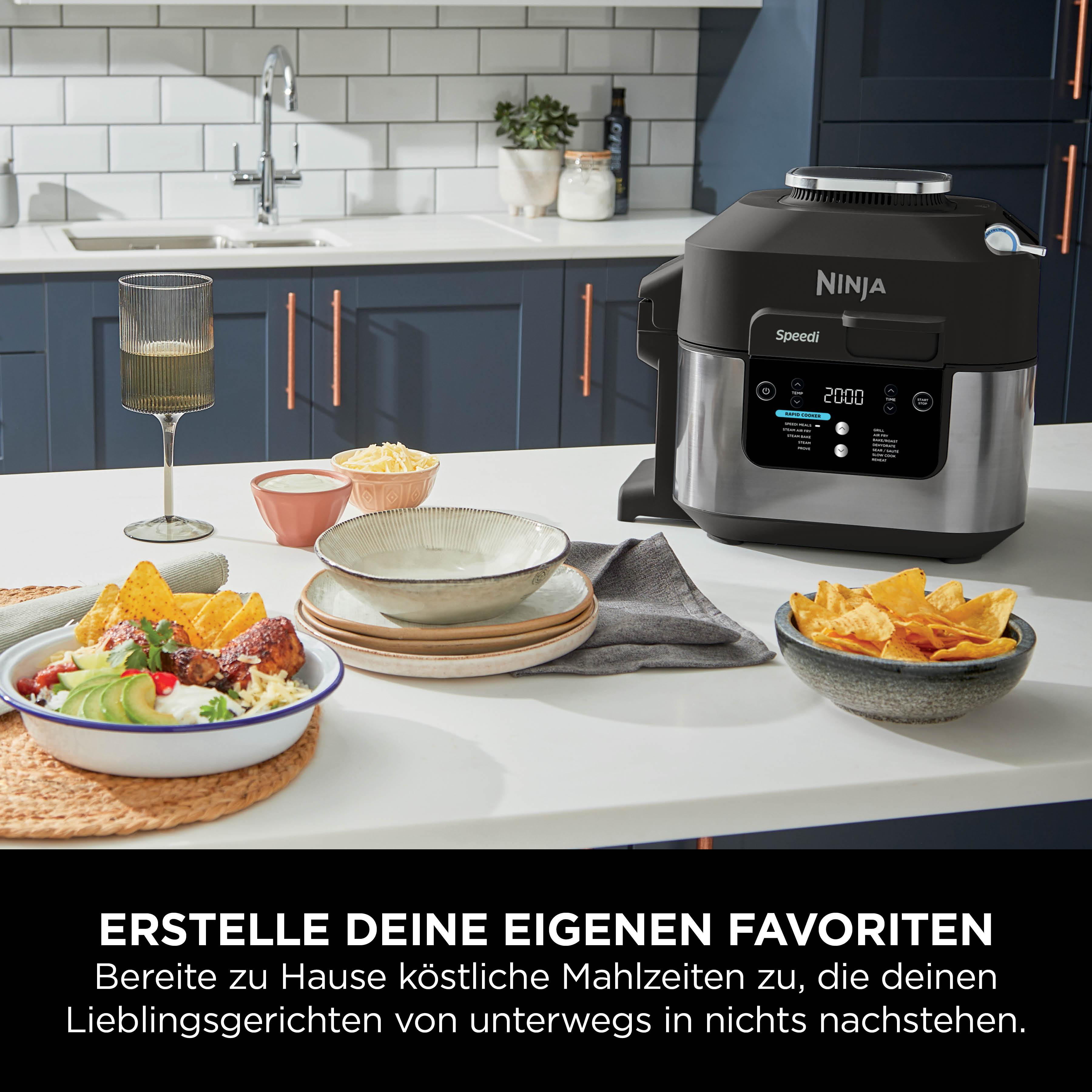 Küchenszene mit Essen, Ninja Speedi und Weinglas. Enthält Schalen mit Essen und eine Heißluftfritteuse.