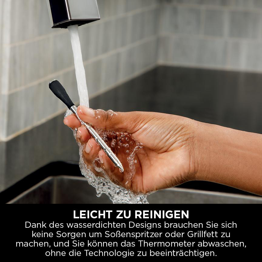 Eine Hand hält ein Thermometer unter fließendem Wasser. Das Thermometer ist silber und schwarz, Wasser spritzt herum.
