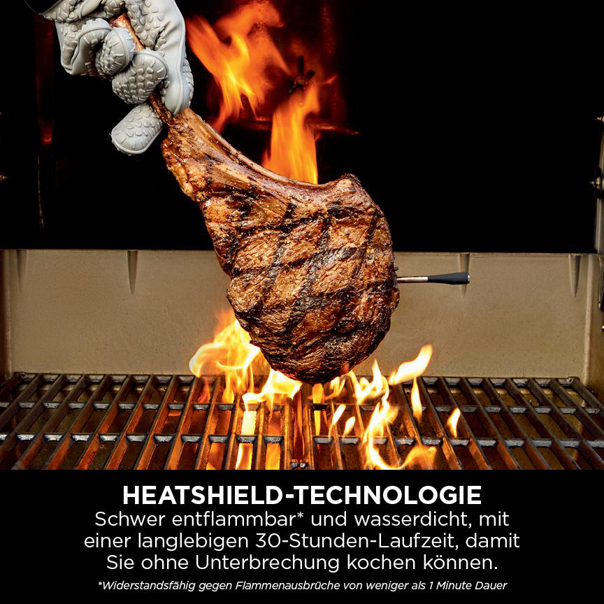 Ein großes, gegrilltes Steak wird mit einem Kochhandschuh über einem Grill mit Flammen gehalten. Text unten: „HEATSHIELD-TECHNOLOGIE“.