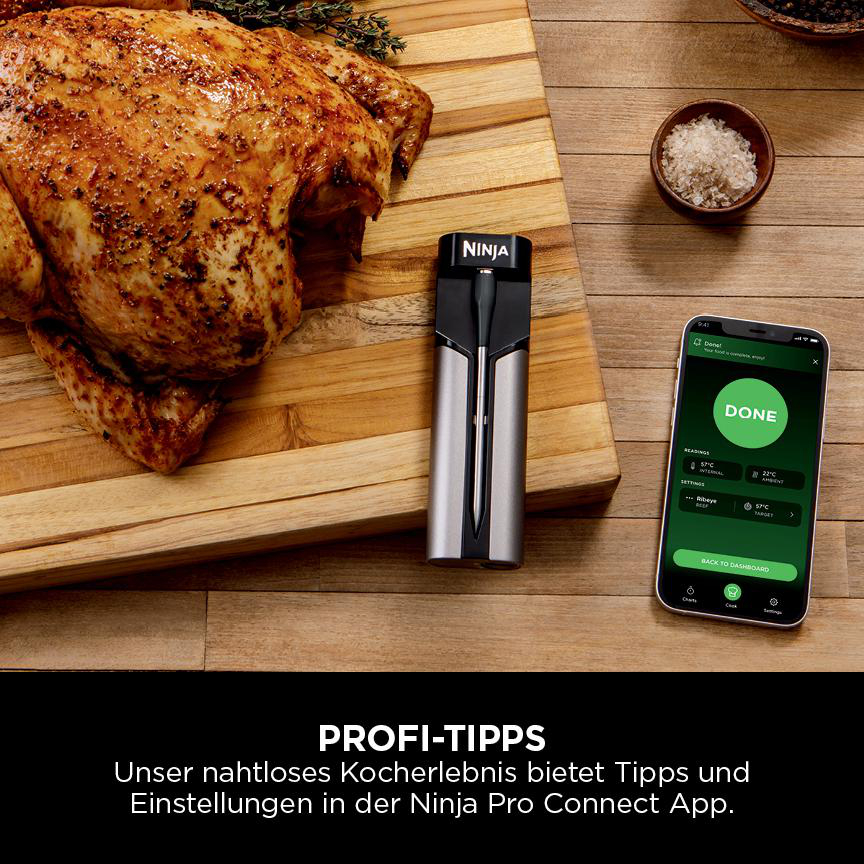 Gebratenes Huhn auf einem Holzbrett mit Thermometer, Smartphone mit 'DONE', Salz und Pfeffer.