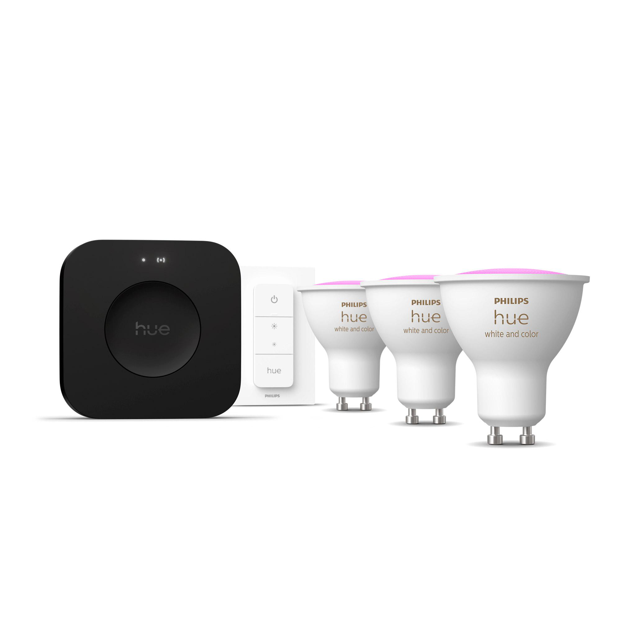 Das Bild zeigt eine schwarze Philips Hue Bridge, eine weiße Fernbedienung und drei weiße und pinkfarbene Hue-Glühbirnen.
