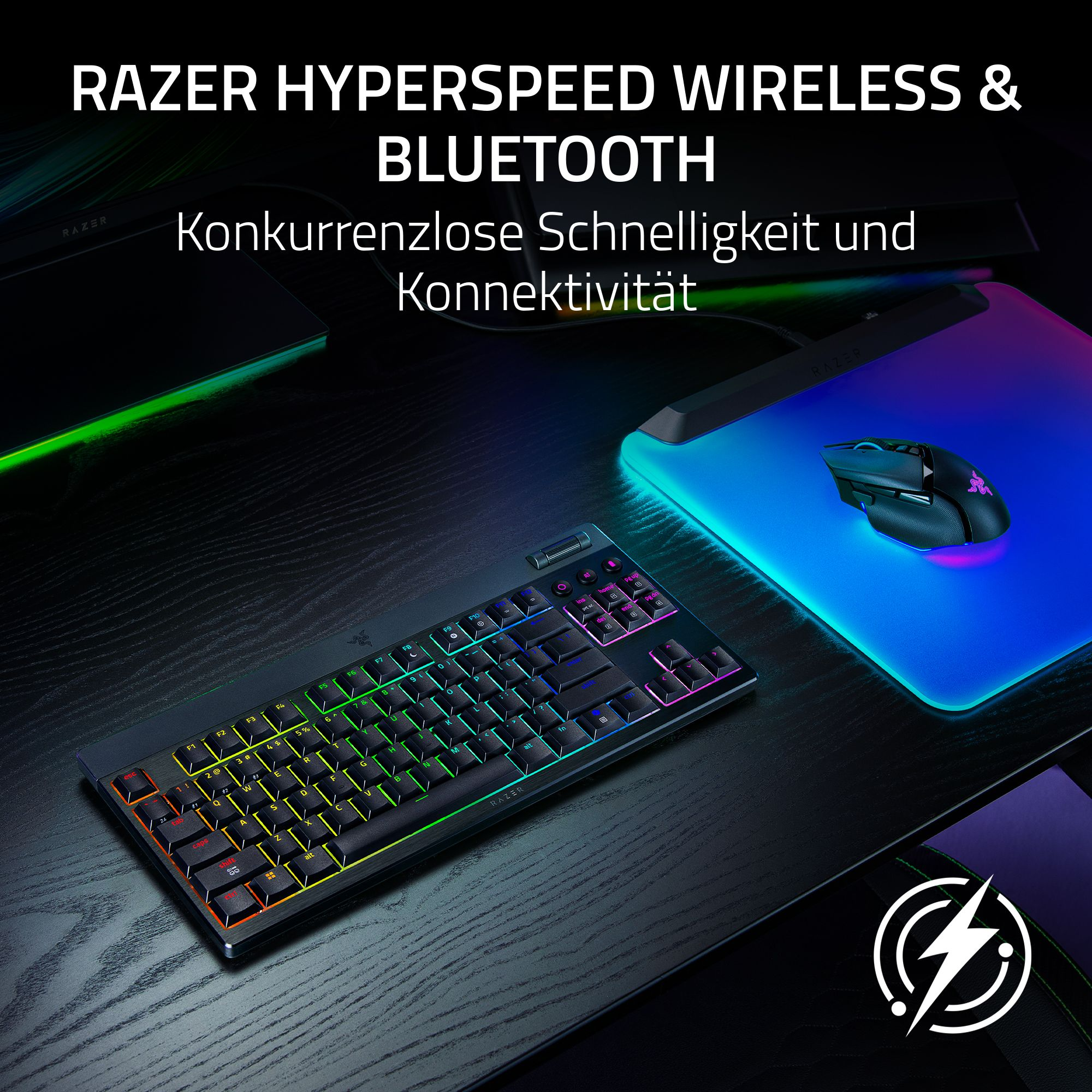 Schwarze Tastatur und Maus mit RGB-Beleuchtung auf einem schwarzen Schreibtisch. Razer-Logo sichtbar.