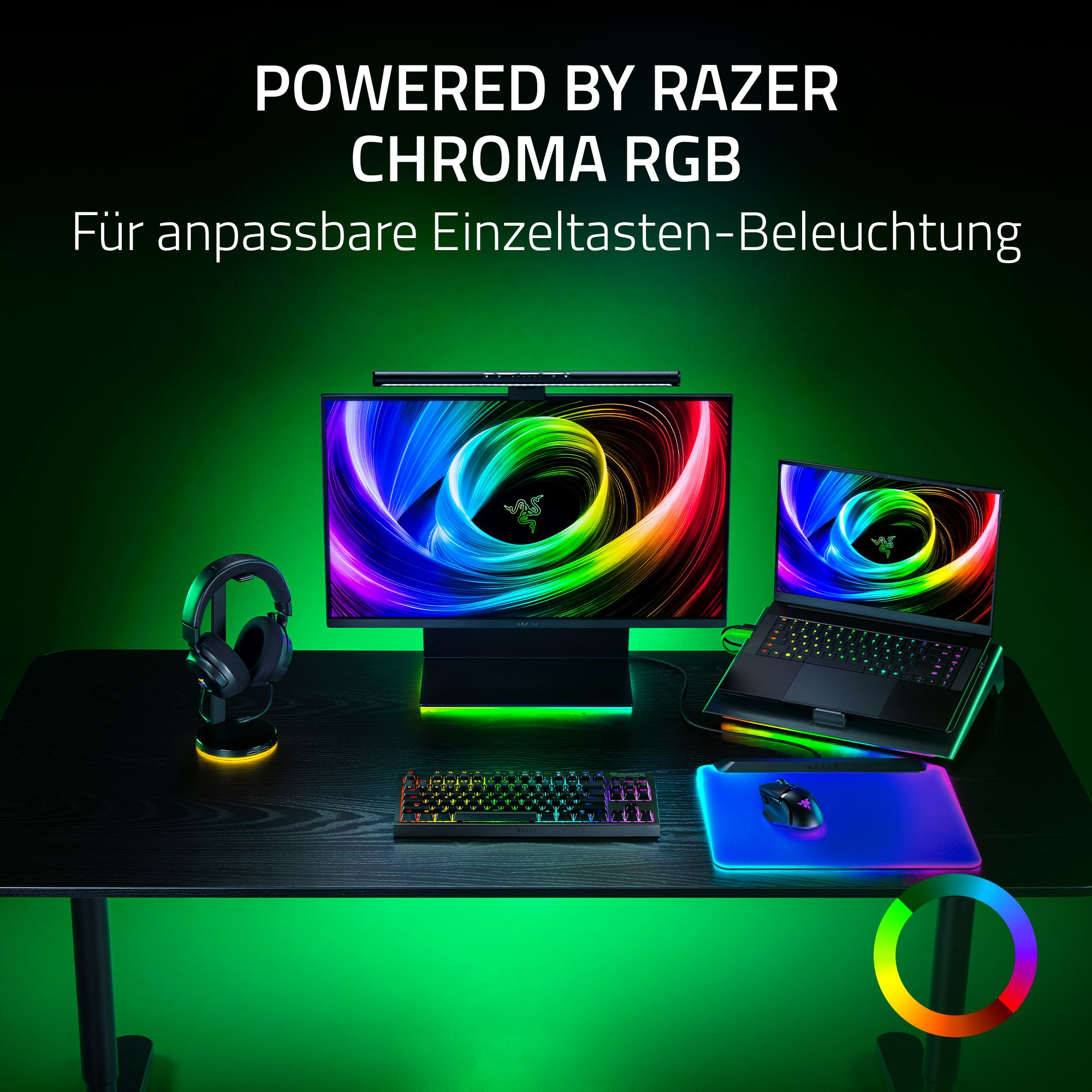 Ein Schreibtisch-Setup mit Razer-Produkten. Monitor, Laptop, Tastatur, Maus, Kopfhörer, alles mit RGB-Beleuchtung, stehen auf einem schwarzen Schreibtisch.