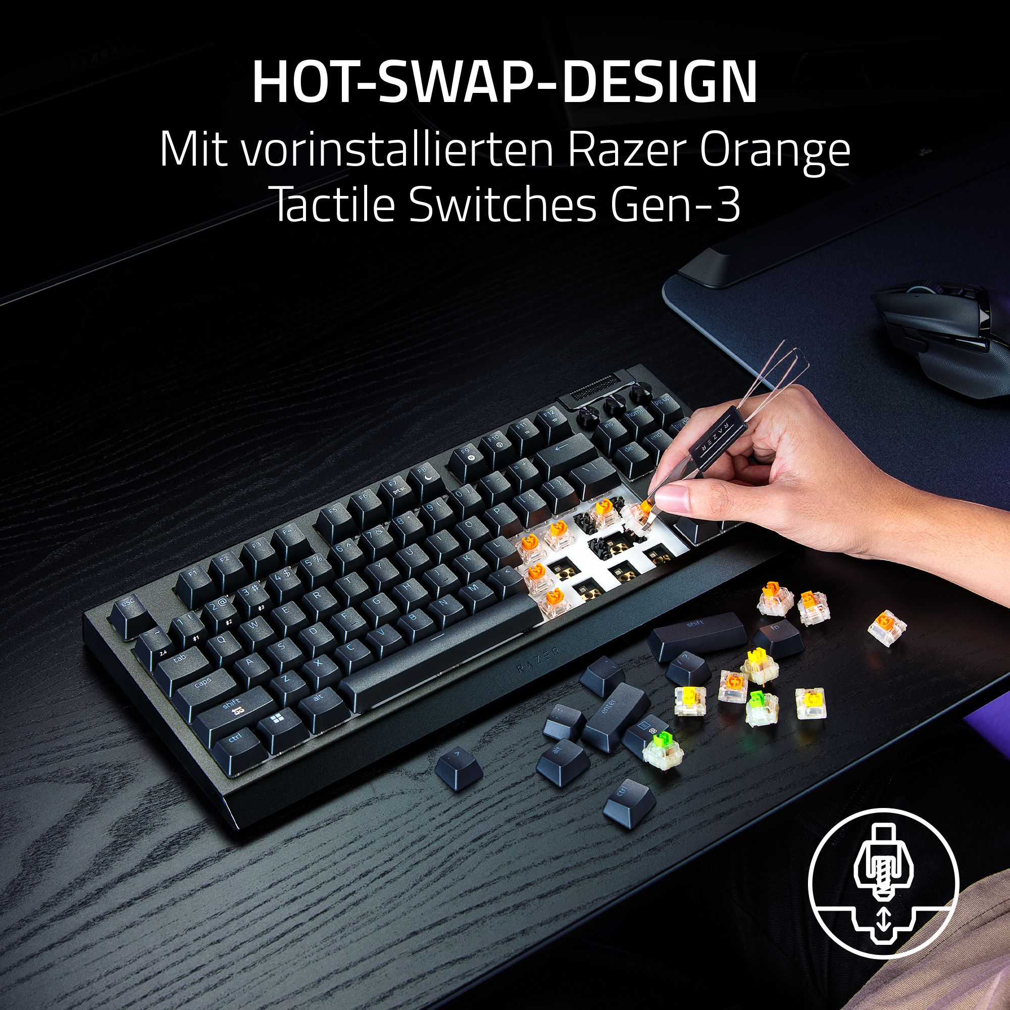 Eine Person tauscht Tastaturtasten aus. Die Tastatur liegt auf einem schwarzen Schreibtisch. Einige Tasten sind entfernt.