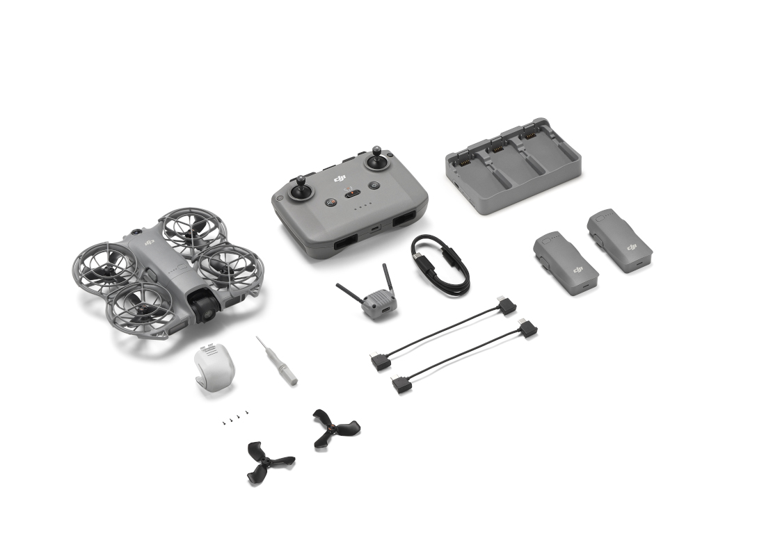 Zestaw drona, w tym dron, kontroler, ładowarka, baterie, kable i akcesoria, ułożone na białej powierzchni.
