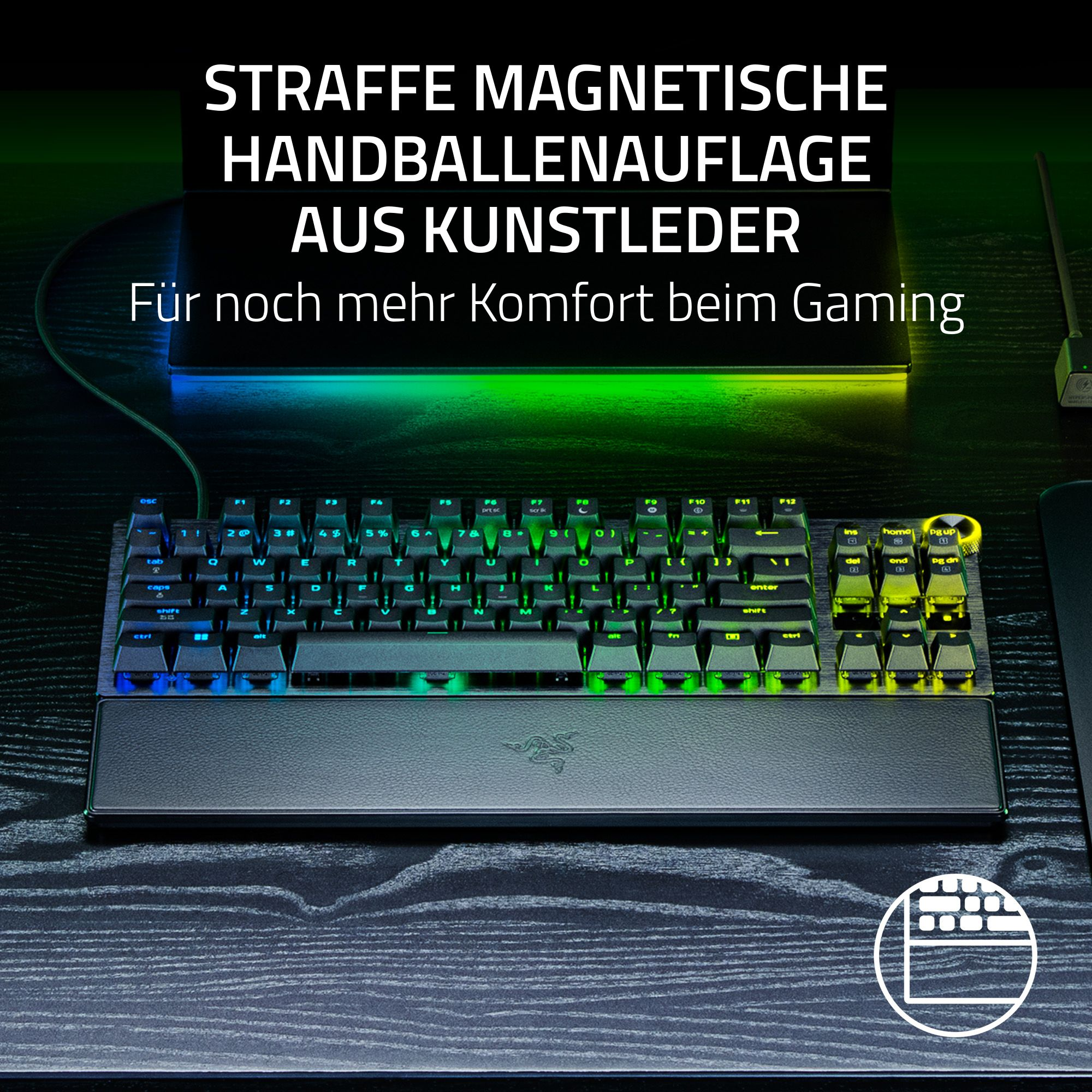 Eine Gaming-Tastatur mit Handballenauflage auf einem Holztisch, beleuchteten Tasten und Text darüber.