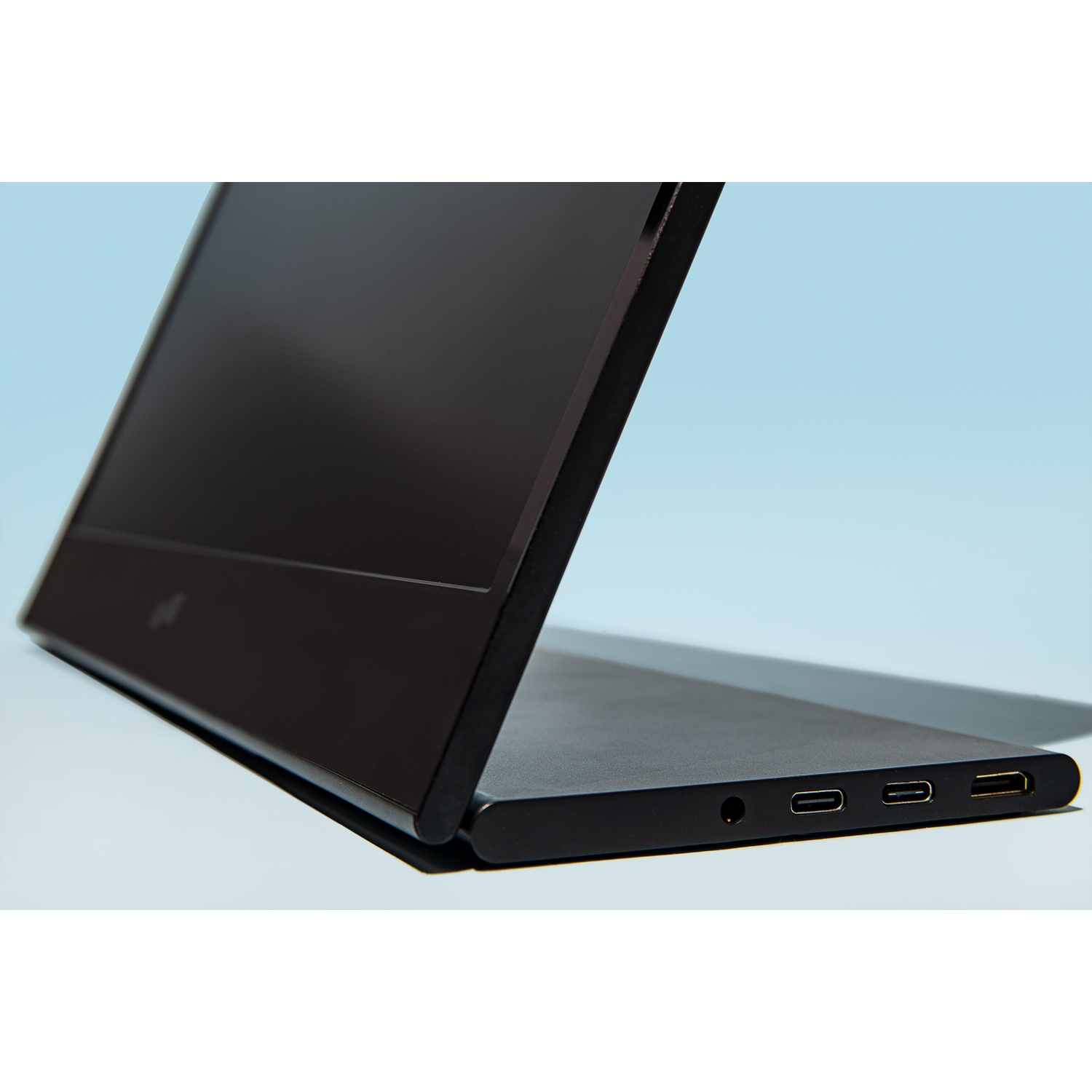 A black laptop is partially open against a light blue background. Ports are visible on the side.