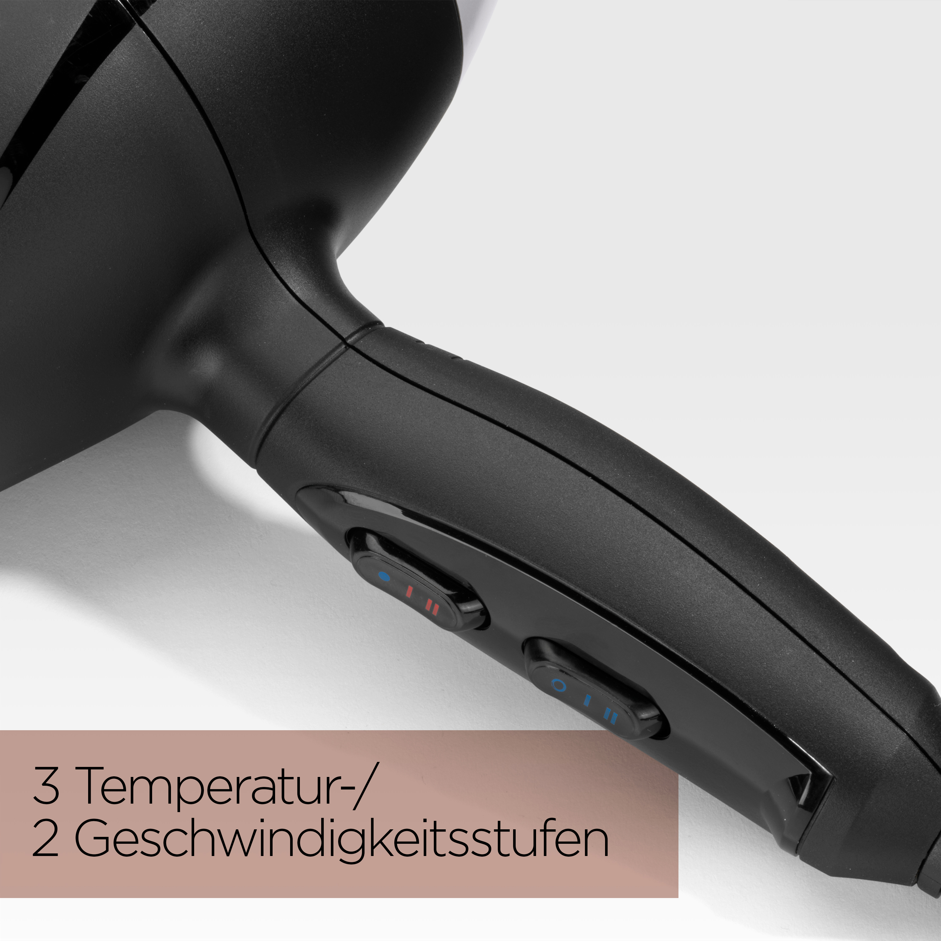 Nahaufnahme eines schwarzen Haartrocknergriffs mit Knöpfen. Text zeigt 3 Temperatur- und 2 Geschwindigkeitseinstellungen.