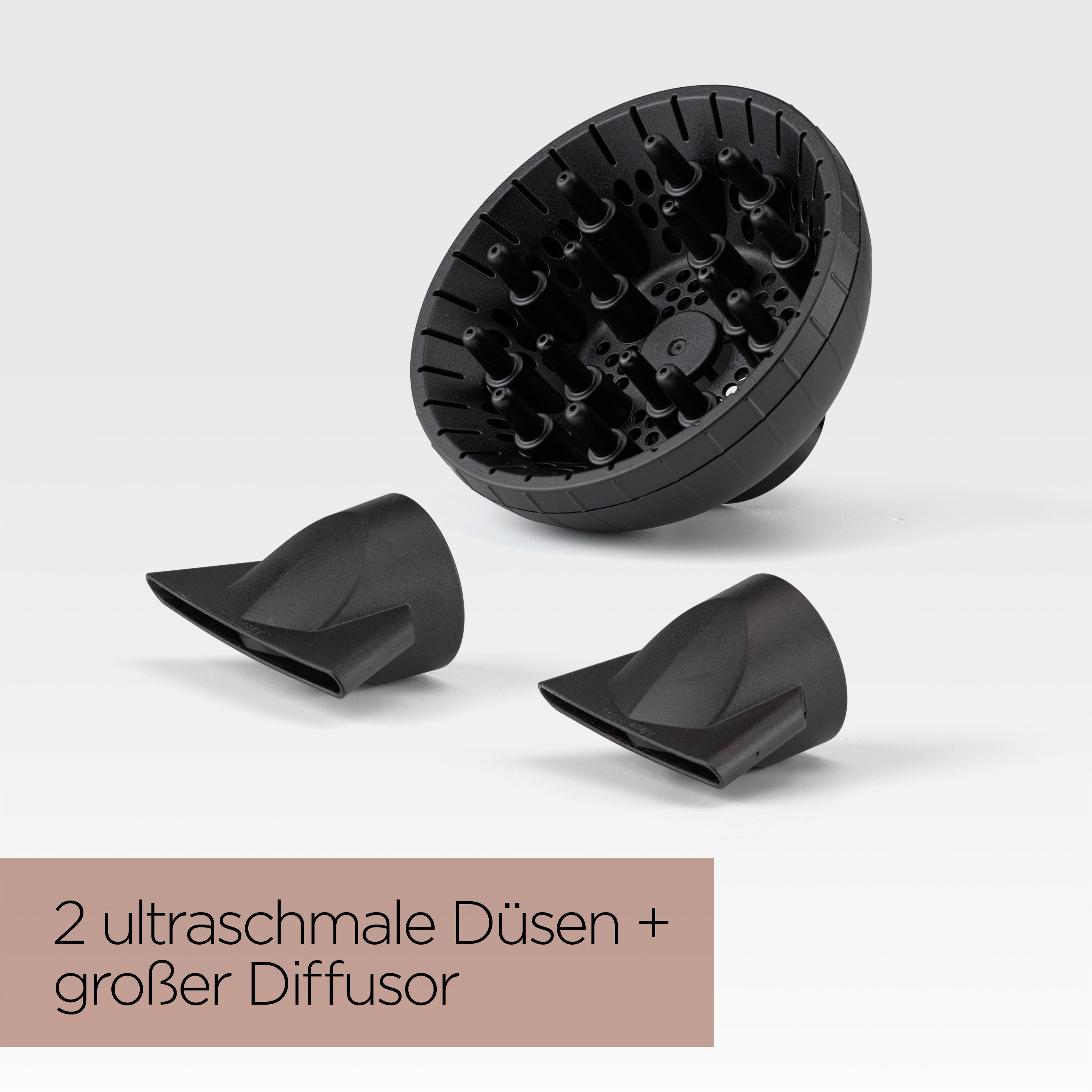 Schwarze Haartrockneraufsätze auf Weiß. Enthält einen Diffusor und zwei Düsen. Text auf Deutsch vorhanden.