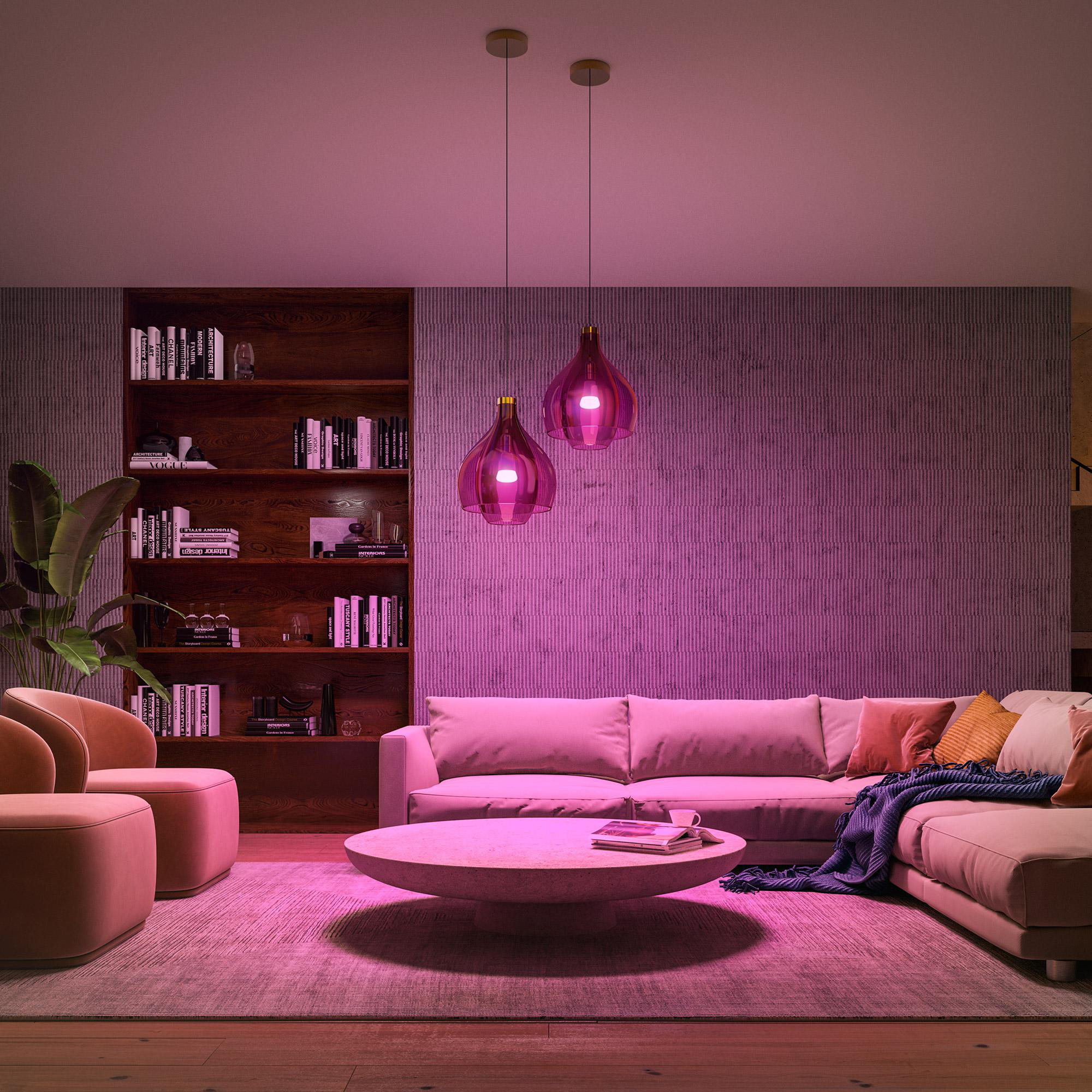Wohnzimmer mit rosa Beleuchtung, Sofa, Sesseln, Couchtisch, Teppich, Bücherregal und dekorativen Pendelleuchten.