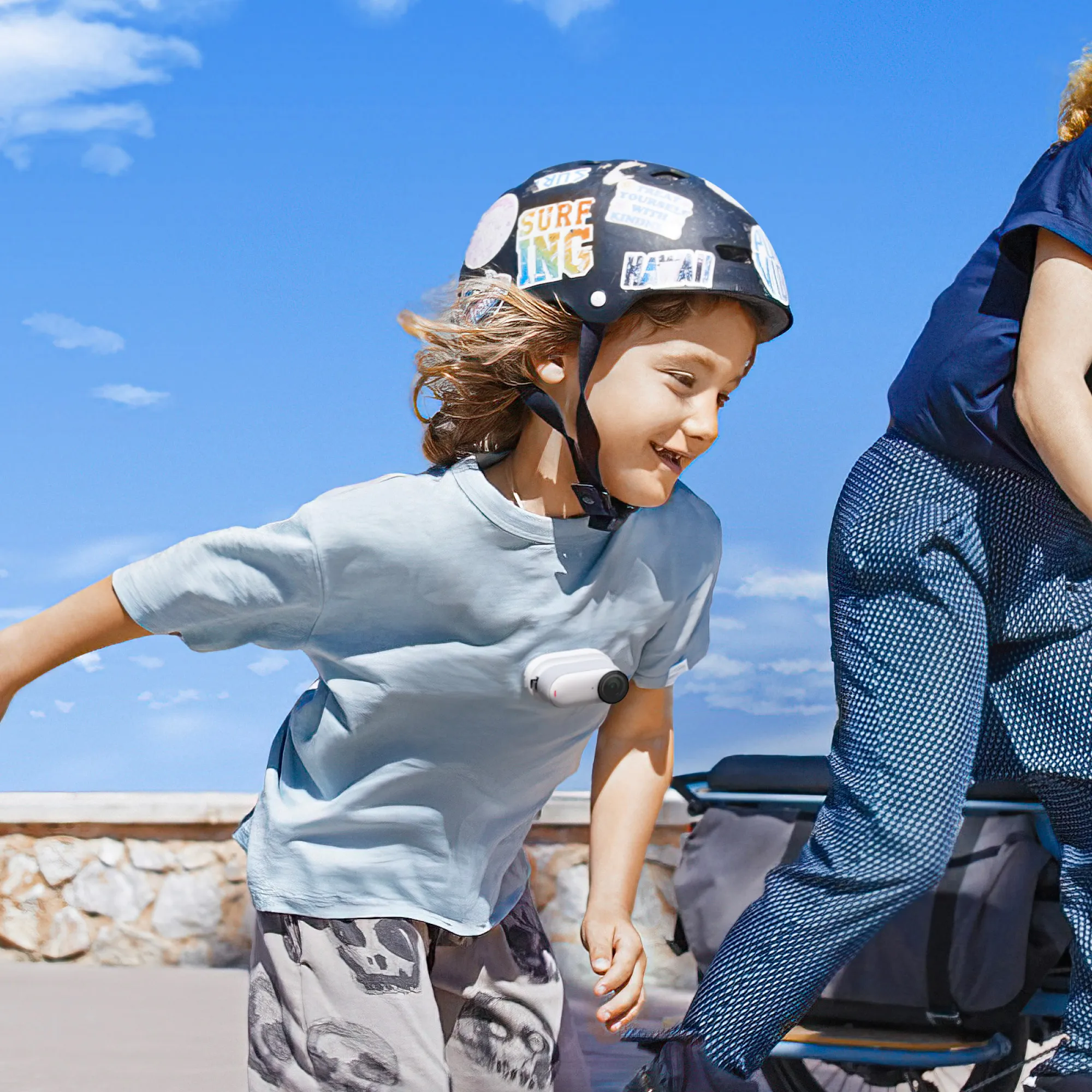 Ein Kind mit Helm fährt Rollschuh. Blauer Himmel im Hintergrund. Ein Erwachsener ist teilweise sichtbar.