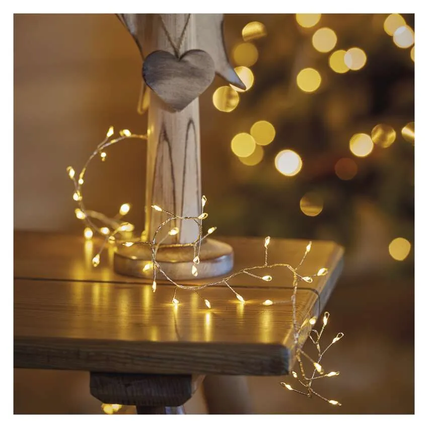 Egy faasztal tündérfényekkel, egy fa dísz szívvel, és bokeh fények a háttérben.