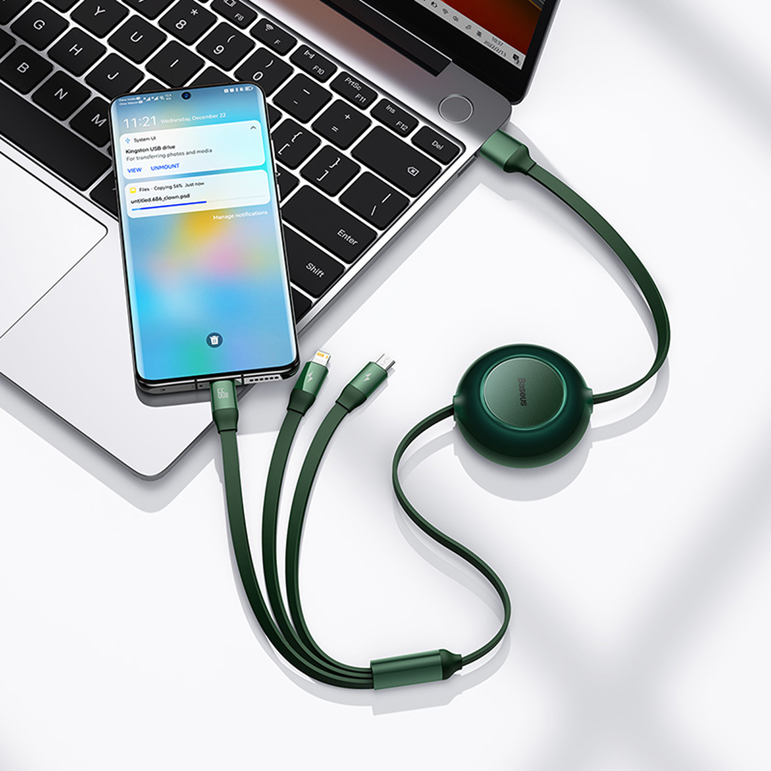 Un teléfono conectado a una laptop mediante un cable de carga verde. El teléfono muestra notificaciones. También hay un concentrador verde conectado.