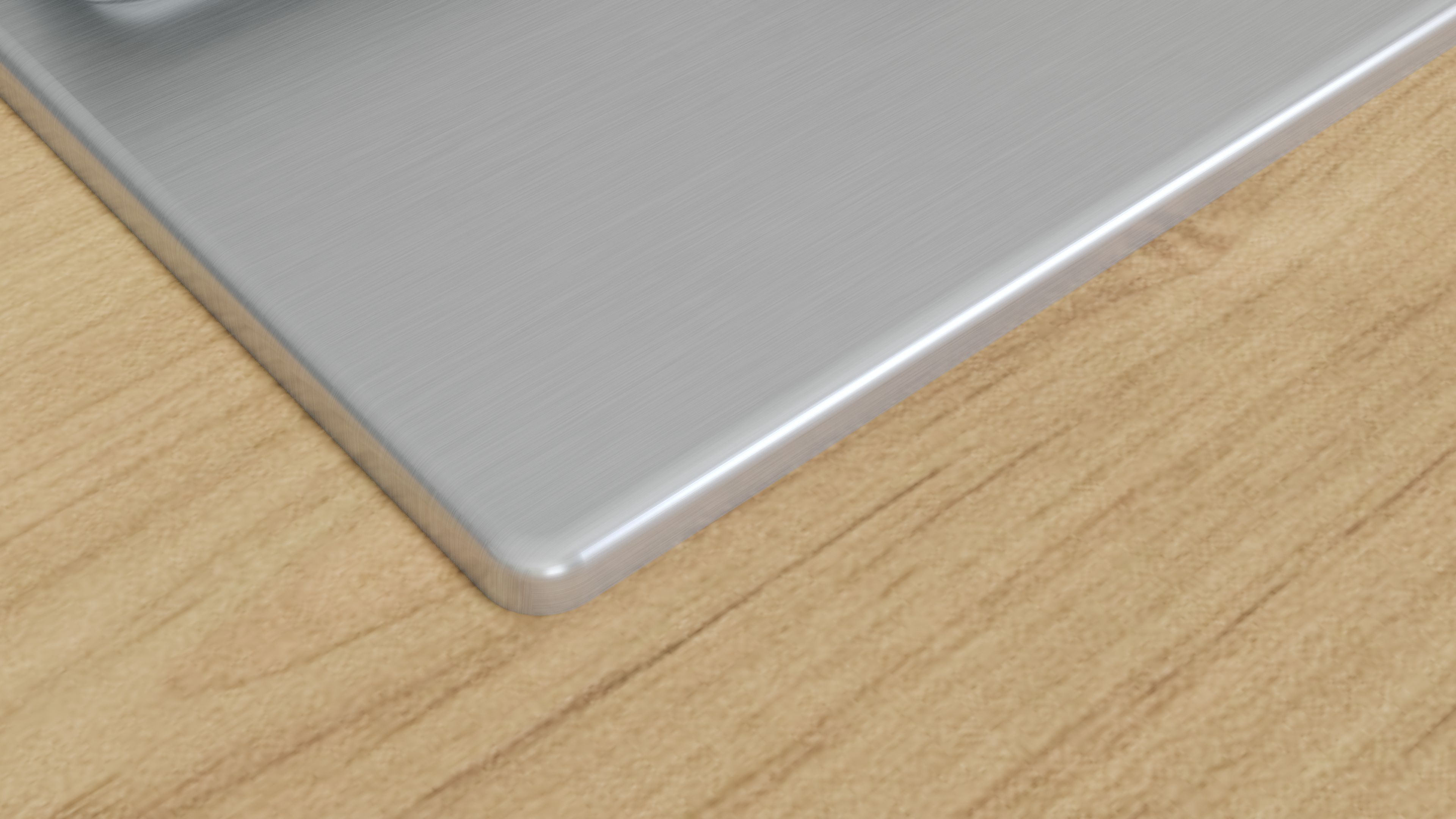 Primer plano de un objeto metálico rectangular con bordes redondeados, sobre una superficie de madera con vetas visibles.