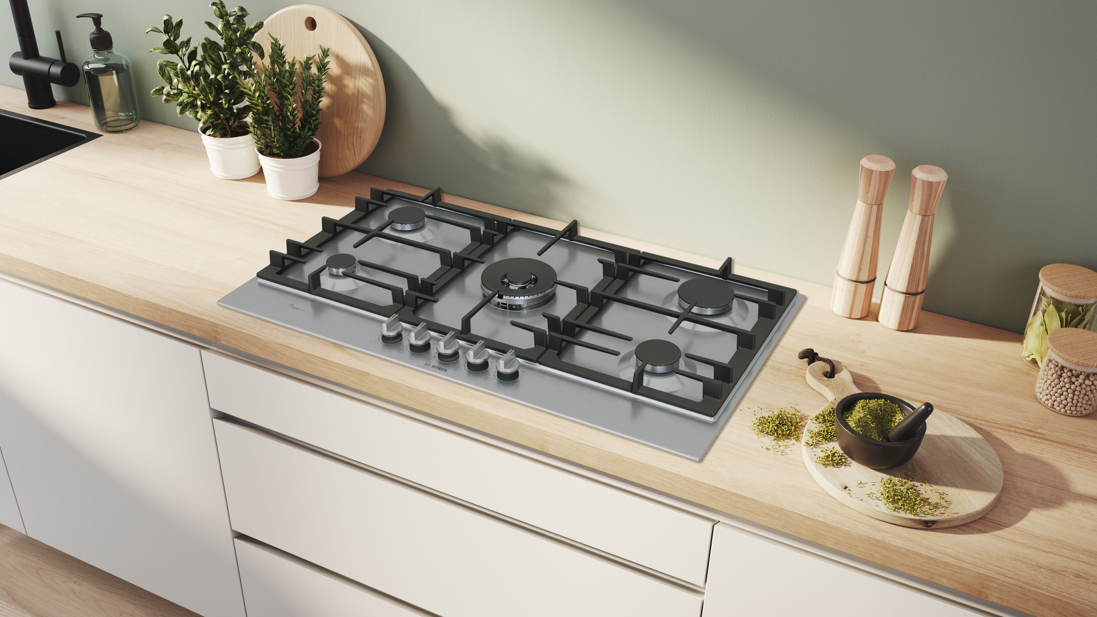 Una cocina de gas de acero inoxidable con rejillas negras se encuentra en una encimera de madera. Hierbas y especias lo rodean. Armarios blancos.