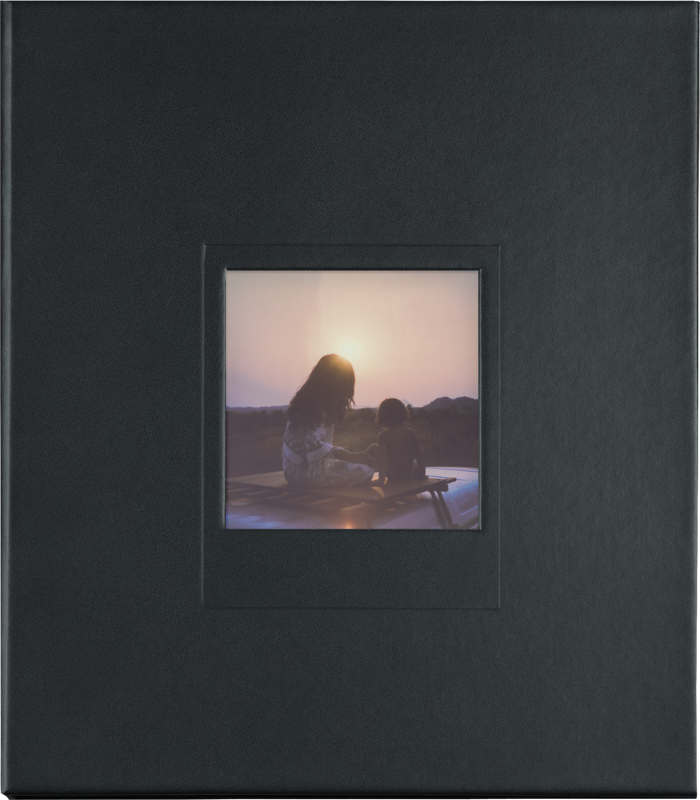 Una foto en un álbum negro muestra a una persona y un niño en un coche con un fondo de puesta de sol.