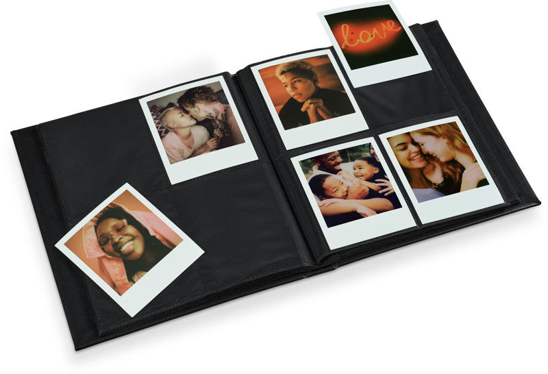 Álbum de fotos abierto con fotos polaroid. Las fotos muestran personas abrazándose, sonriendo y la palabra 'amor'. Álbum negro sobre una superficie negra.