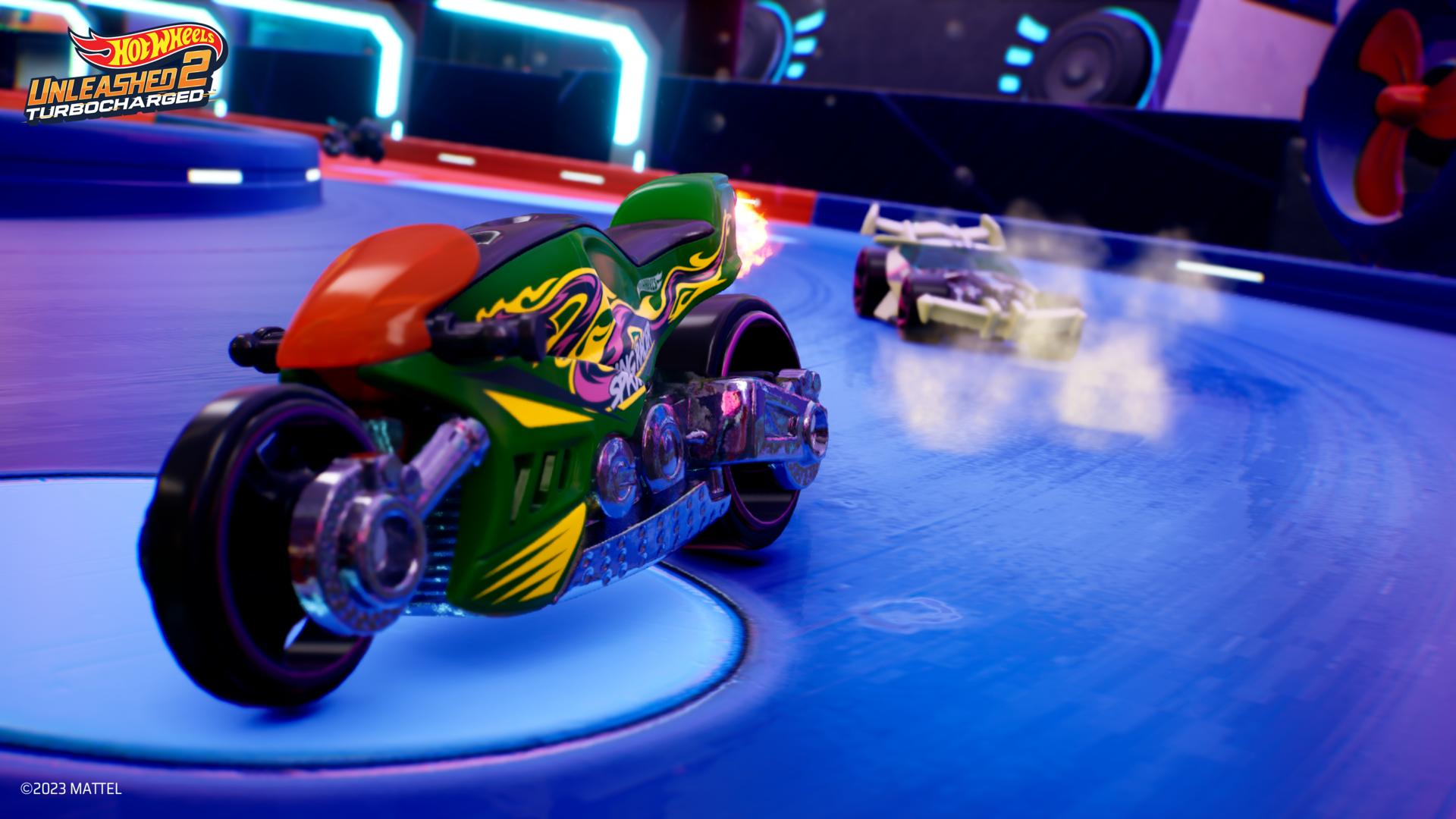 Una moto verde e arancione corre su una pista blu, con una seconda auto sullo sfondo. La scena è tratta da un gioco Hot Wheels.