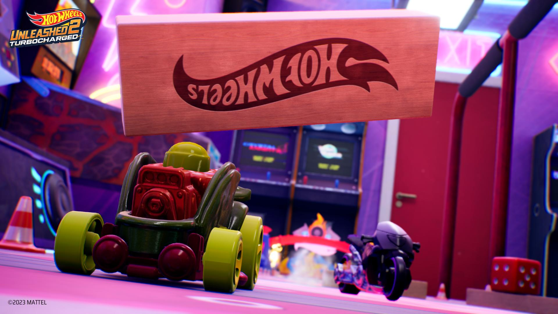 Un'auto e una moto Hot Wheels corrono in una sala giochi. Un grande cartello Hot Wheels è sopra le auto.