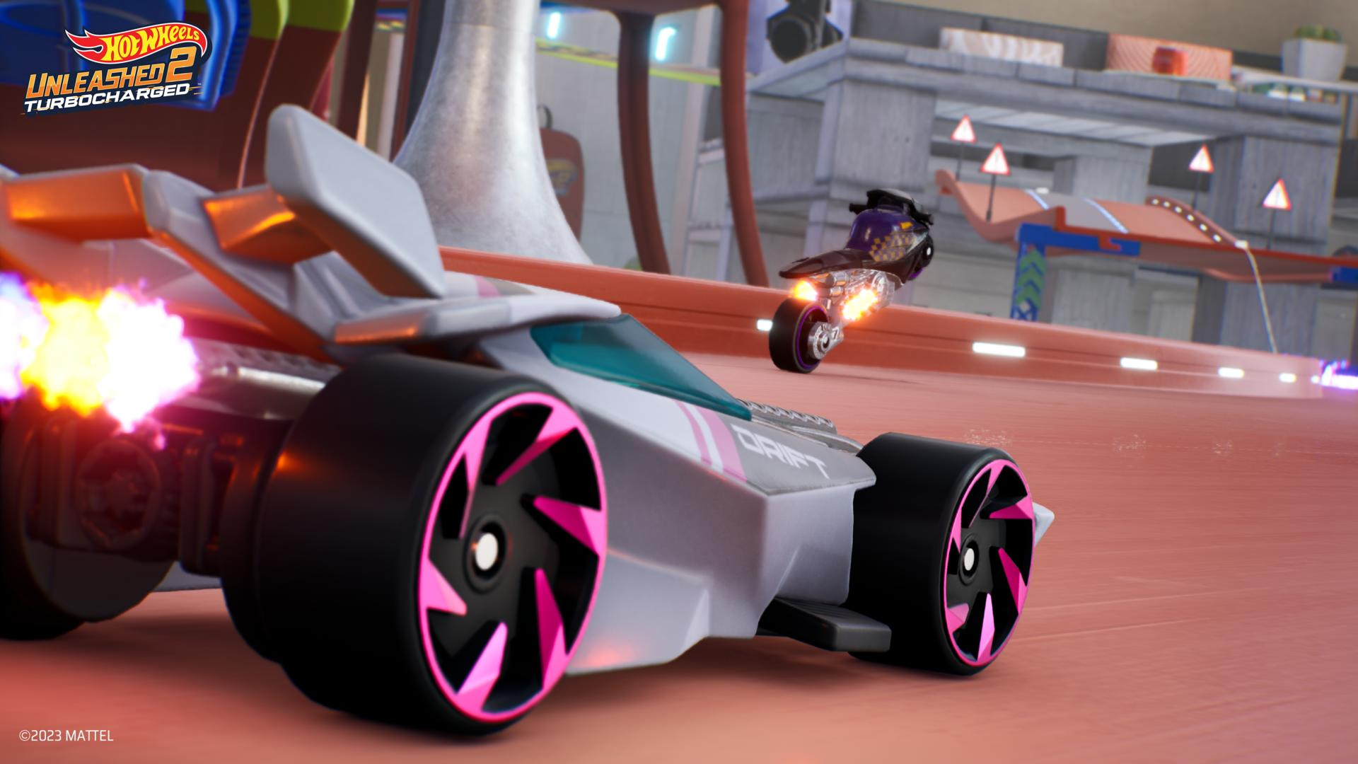 Un'auto Hot Wheels bianca e rosa derapa su una pista. Una moto sullo sfondo, anch'essa in corsa.