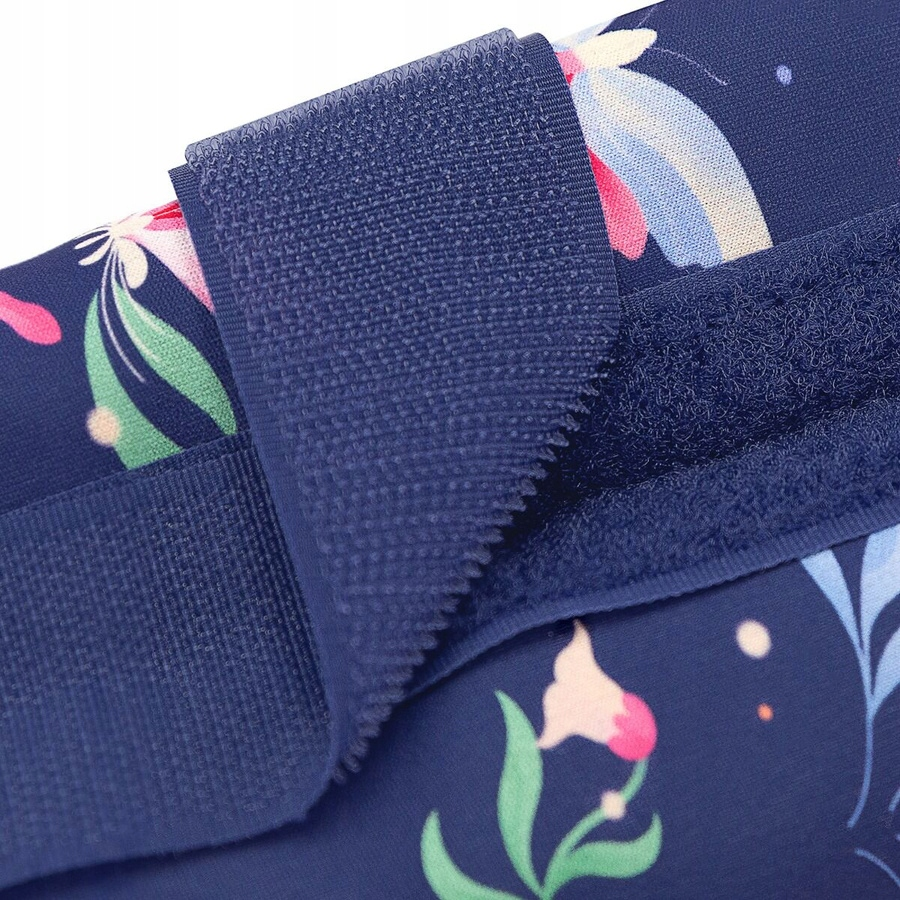 Zbliżenie ciemnoniebieskiej tkaniny z kwiatowymi wzorami. Do tkaniny przymocowany jest ciemnoniebieski pasek na rzep.