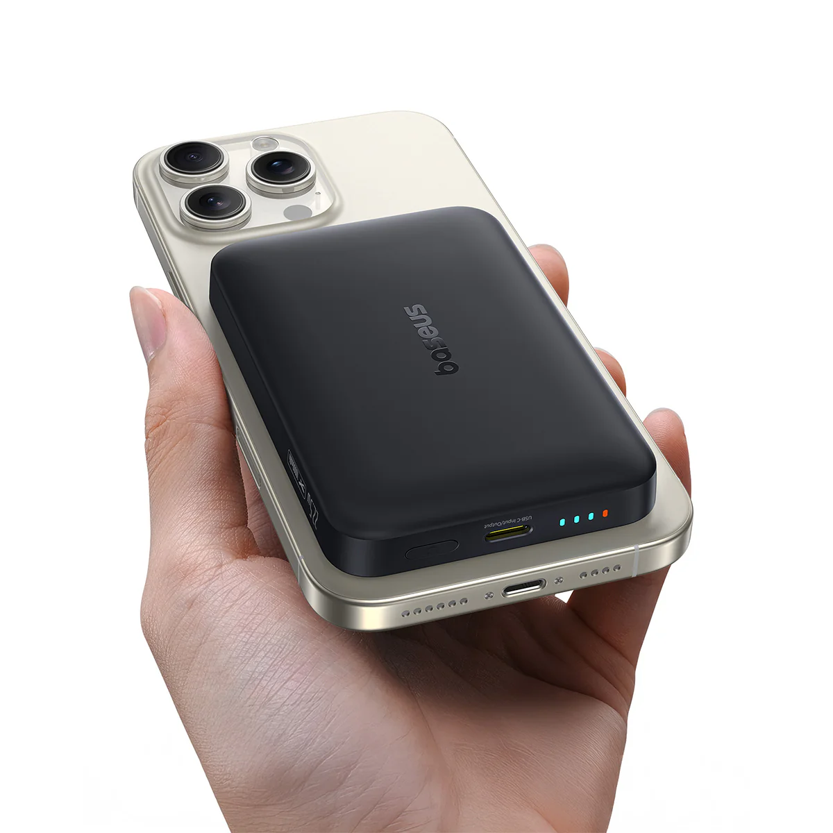Egy kézben egy telefon van, melyre egy fekete power bank van rögzítve. A telefon arany, a power bank fekete. A power bankon lámpák világítanak.