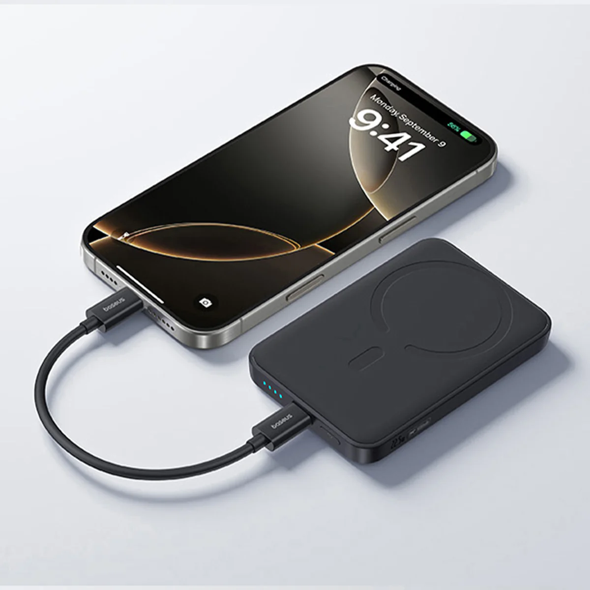 Egy iPhone fekete kábellel töltődik, ami egy fekete power bankhoz csatlakozik. A telefon 9:41-et és az akkumulátor töltöttségét mutatja.