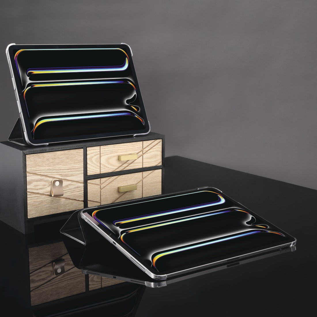 Zwei Tablets mit schwarzen Bildschirmen auf schwarzer Oberfläche. Eines steht auf einer Holzkiste, ein anderes liegt.
