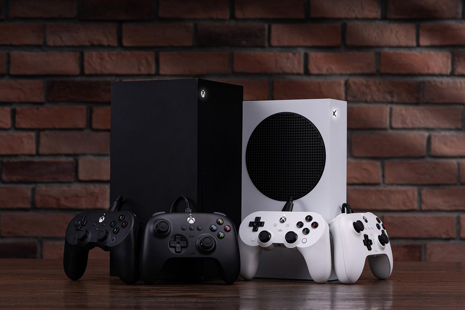 Xbox-Konsolen und -Controller auf Holzoberfläche mit Backsteinmauer im Hintergrund. Schwarz-Weiß-Farbschema.