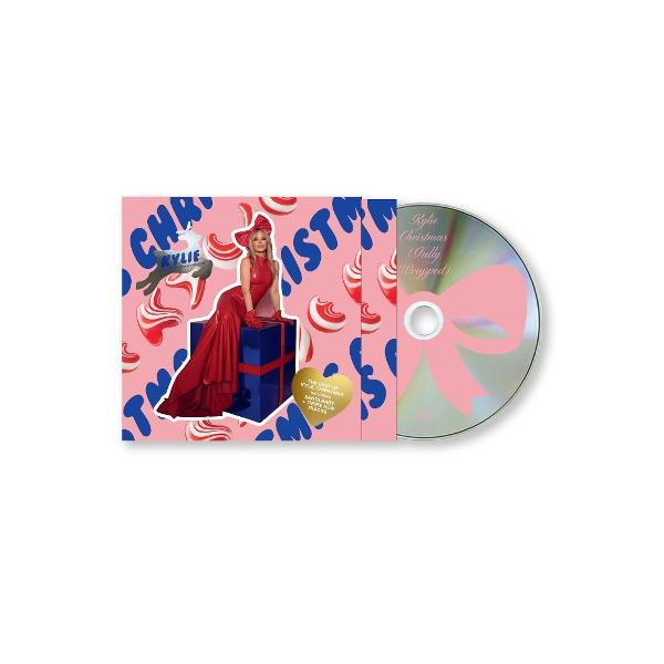 Albumcover: Frau in rotem Kleid, Schleife und blauer Geschenkbox. Pinker Hintergrund mit Zuckerstangen und Text. CD mit rosa Schleife.