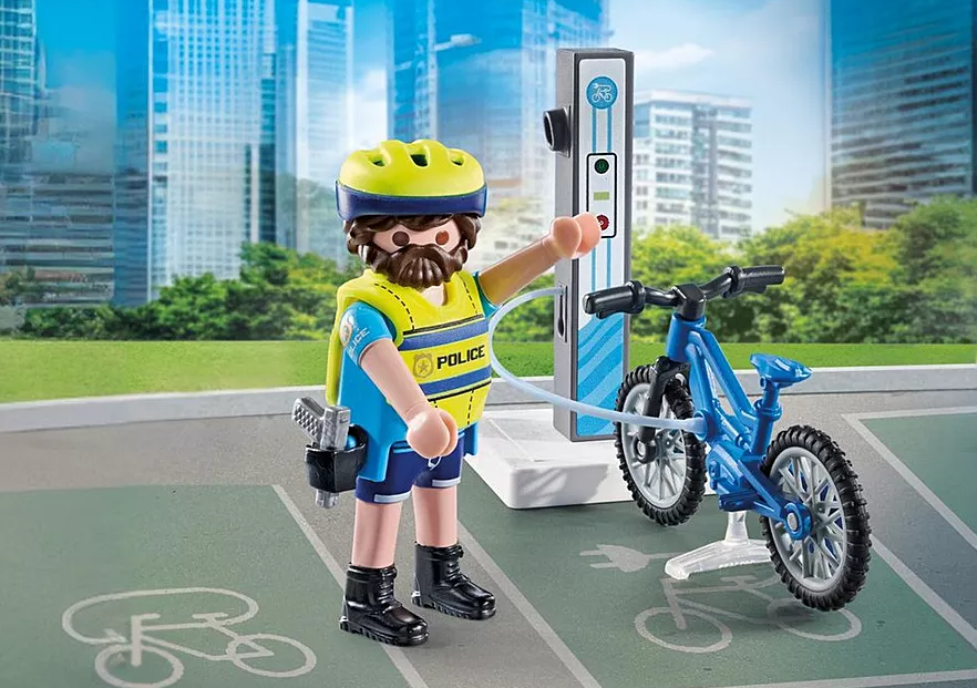 Ein Spielzeugpolizist mit Fahrrad lädt es an einer Ladestation auf. Im Hintergrund sind Stadtgebäude und Bäume zu sehen.