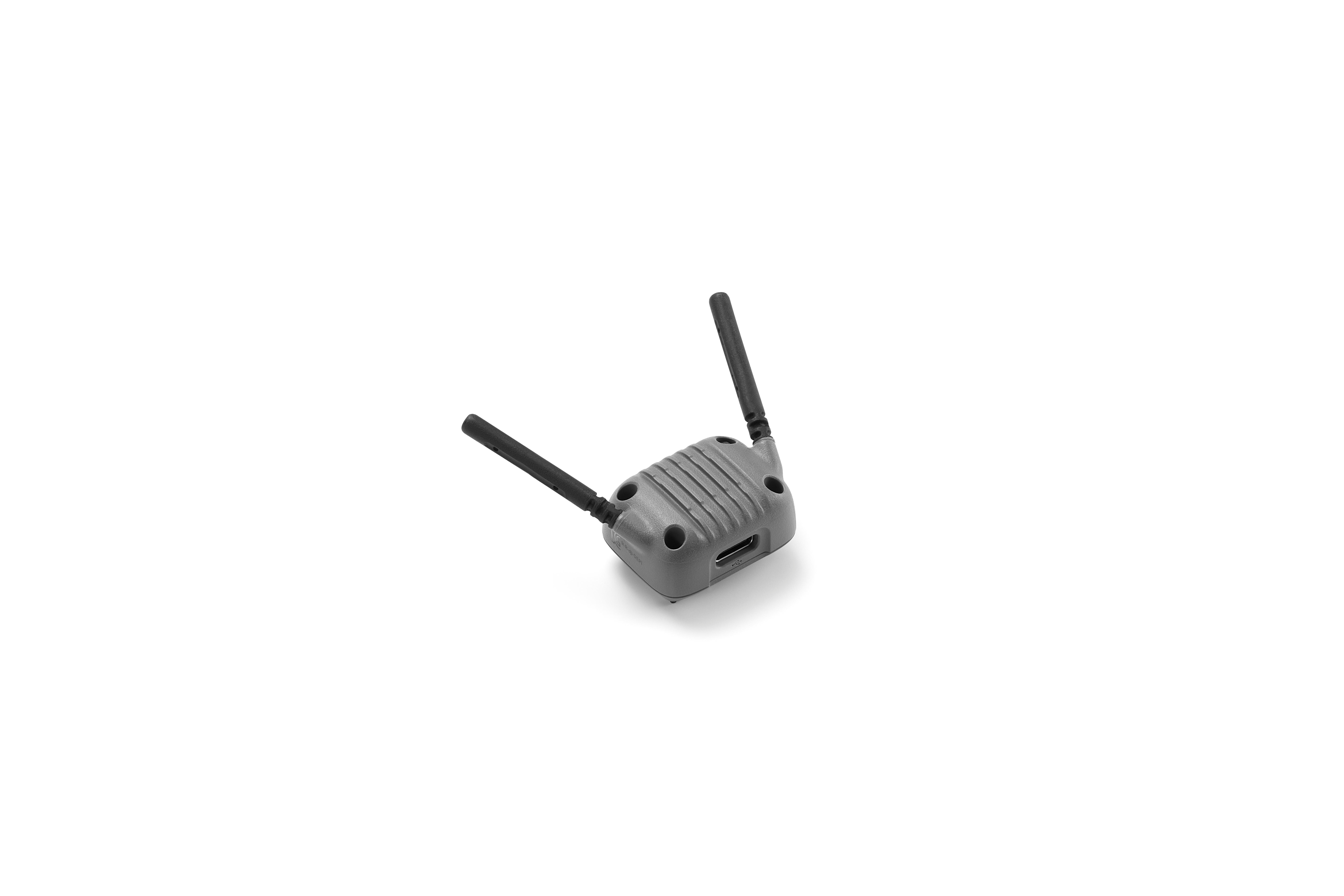 Ein graues Gerät mit zwei schwarzen Antennen liegt auf weißem Grund. Es hat einen USB-Anschluss und Löcher.