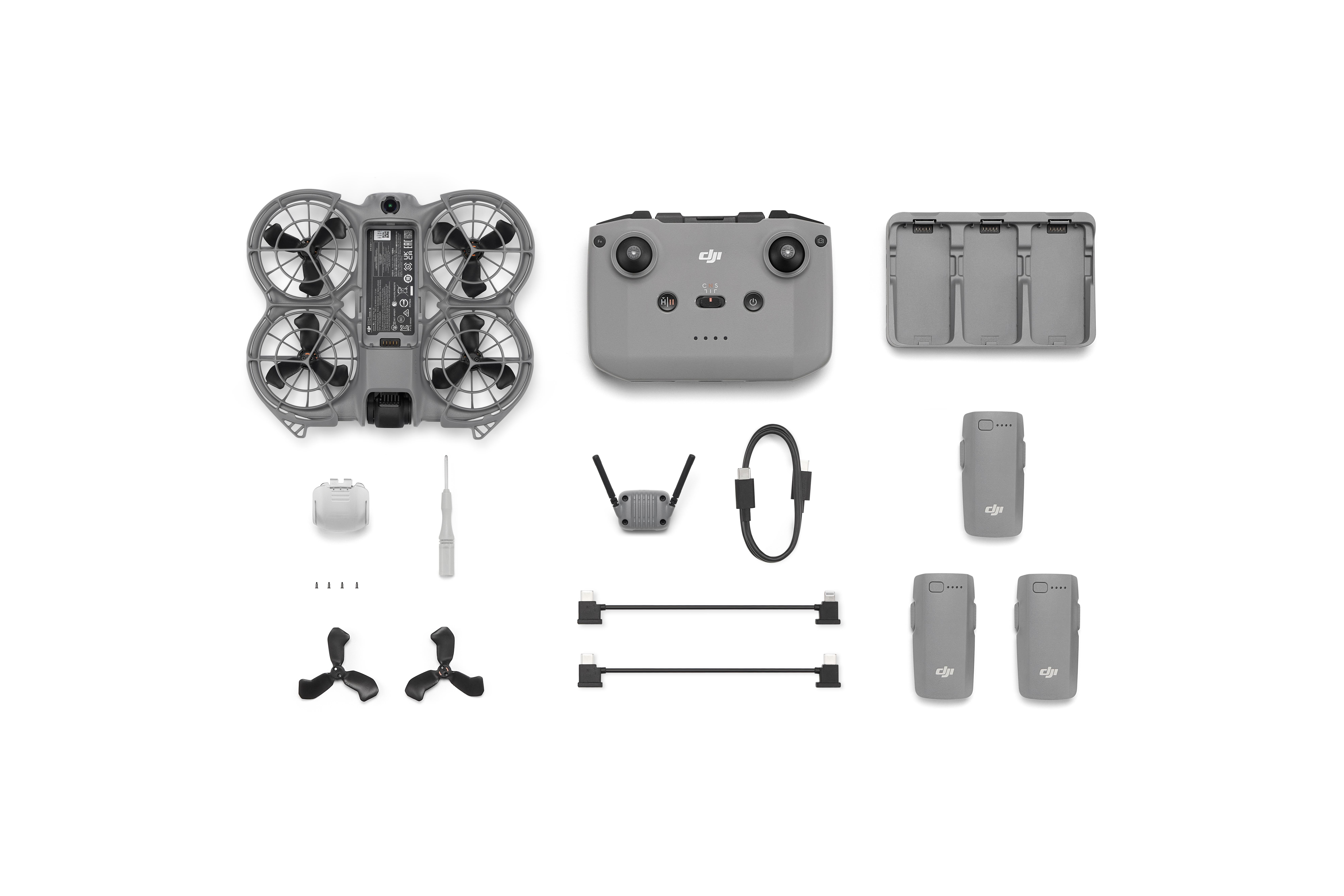 Drohnen-Kit-Komponenten auf weißem Hintergrund. Enthält Drohne, Fernbedienung, Ladegerät, Akkus, Kabel und Zubehör.