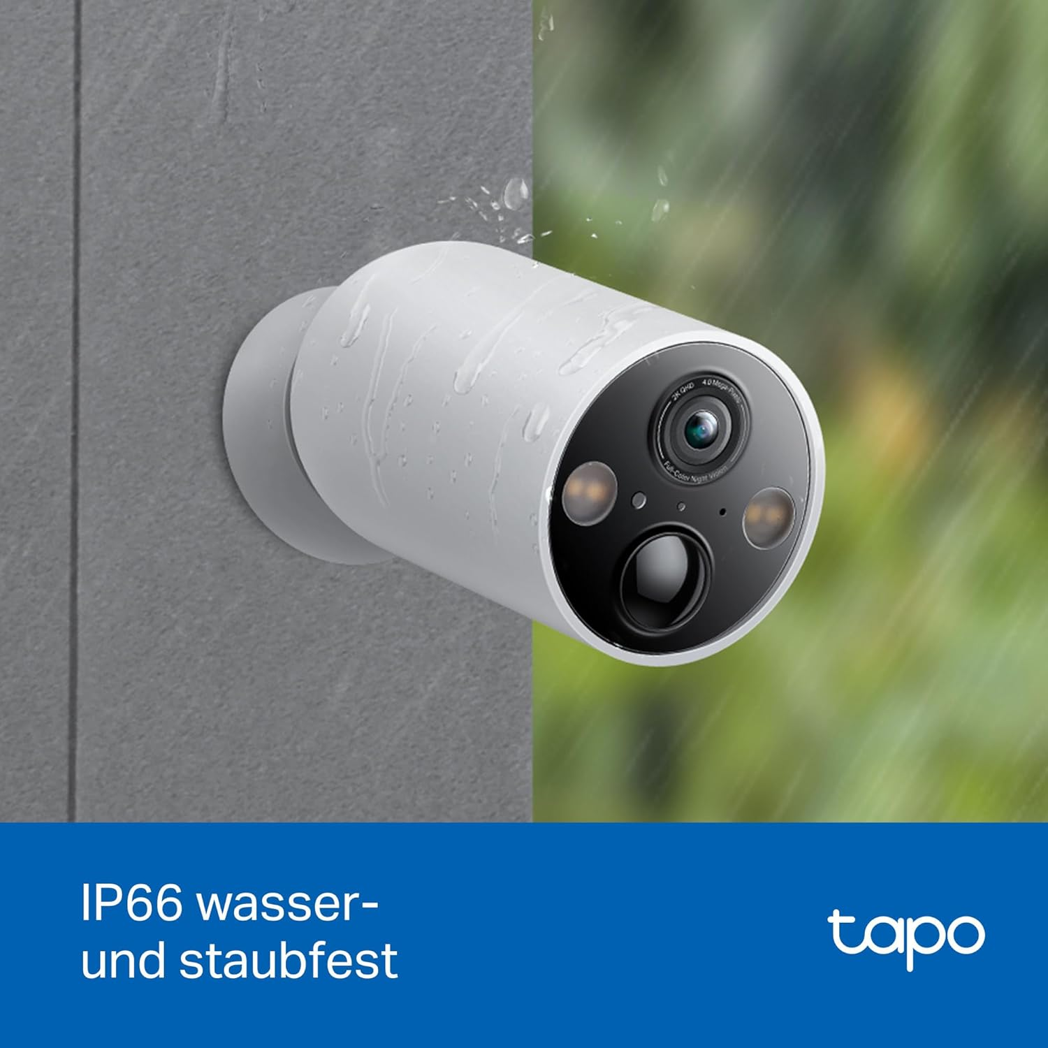Eine weiße Überwachungskamera mit schwarzem Objektiv ist an einer grauen Wand montiert. Regentropfen sind sichtbar. Der Hintergrund ist grün unscharf.