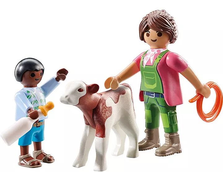 Eine Spielzeugszene zeigt ein Kalb, eine Frau mit einem Seil und ein Kind mit einer Flasche. Das Kalb ist braun und weiß. Die Frau trägt grüne Overalls.