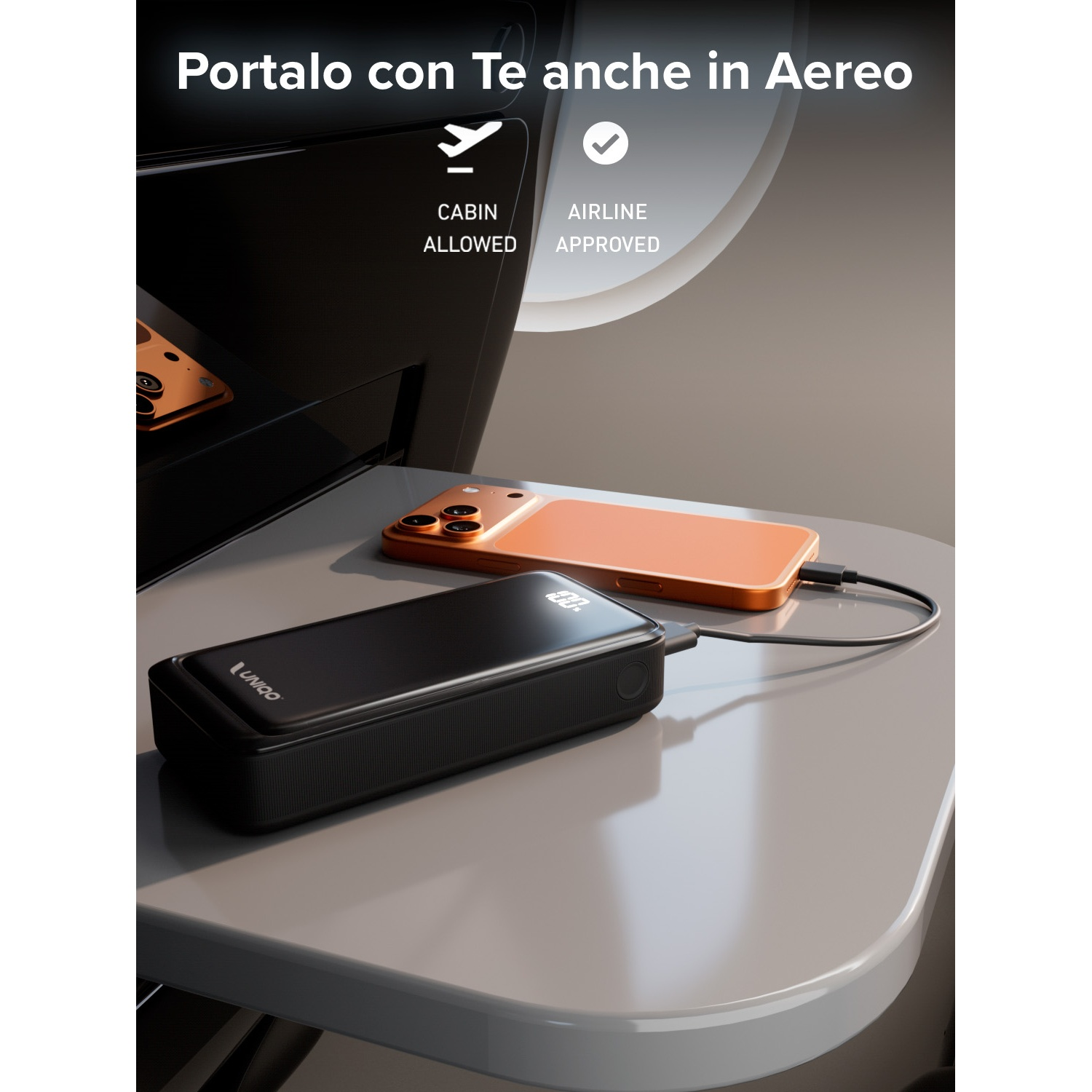 Un power bank nero e un telefono arancione sono su un vassoio grigio, collegati da un cavo. Il testo dice: consentito in cabina.