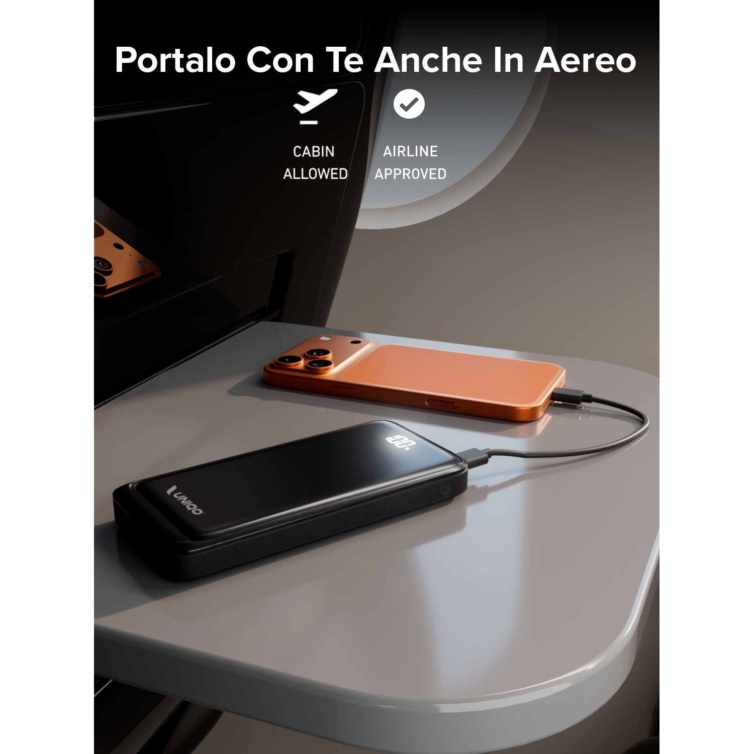 Un power bank nero è collegato a un telefono arancione su una superficie grigia, suggerendo la ricarica in volo. Cabina consentita, approvato dalla compagnia aerea.