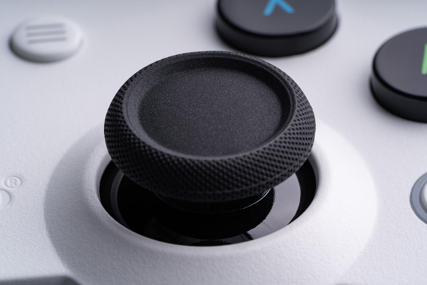 Nahaufnahme eines weißen Gamecontrollers. Der schwarze Joystick steht im Fokus, umgeben von anderen Tasten.