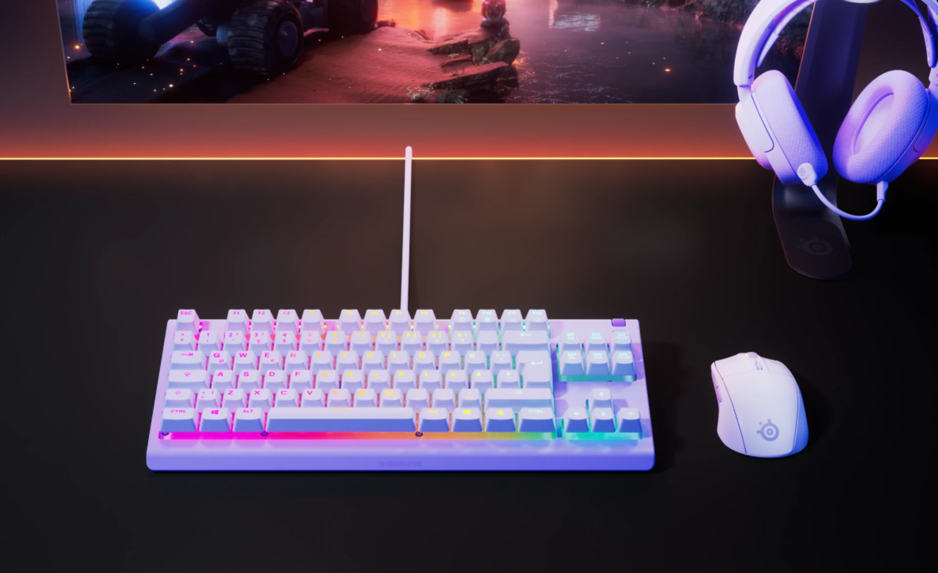 Egy gamer setup billentyűzettel, egérrel és fejhallgatóval. A billentyűzet fehér, színes fényekkel. A háttérben egy monitor látható.