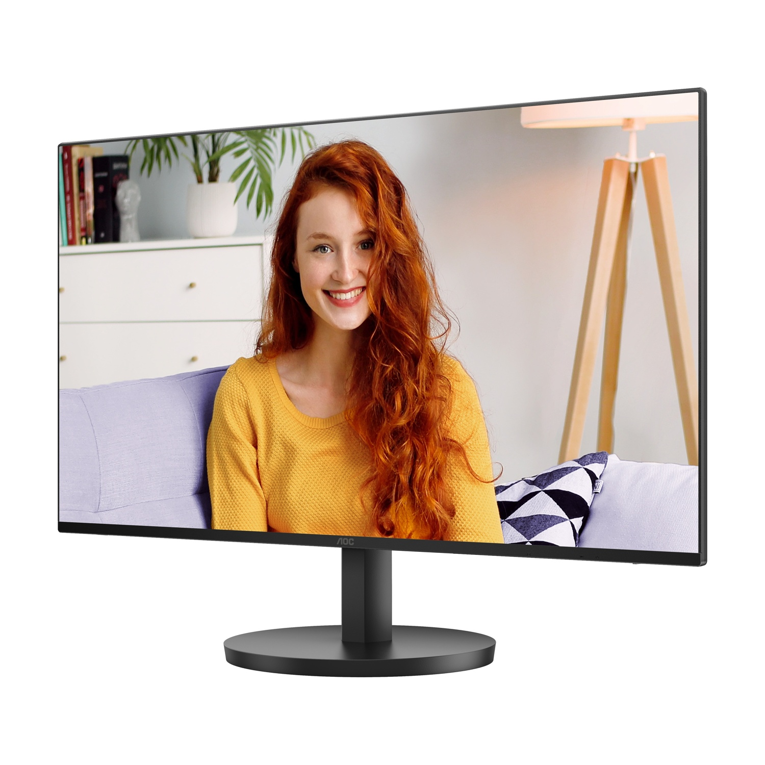 Monitor che mostra una donna dai capelli rossi che sorride. Indossa giallo, seduta su un divano viola. Sfondo con mobili e lampada.