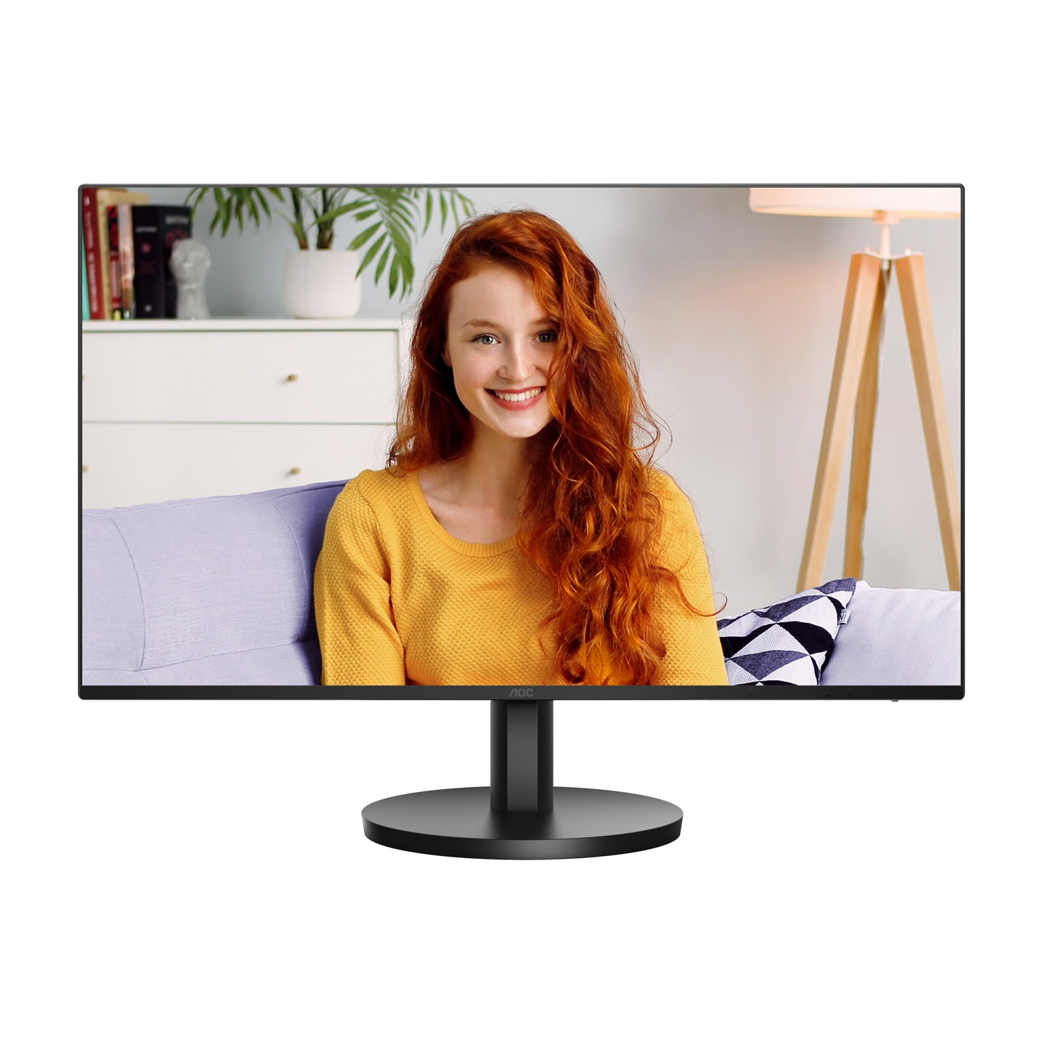 Monitor mostra donna dai capelli rossi che sorride, in giallo. Sfondo: divano, lampada, libreria.